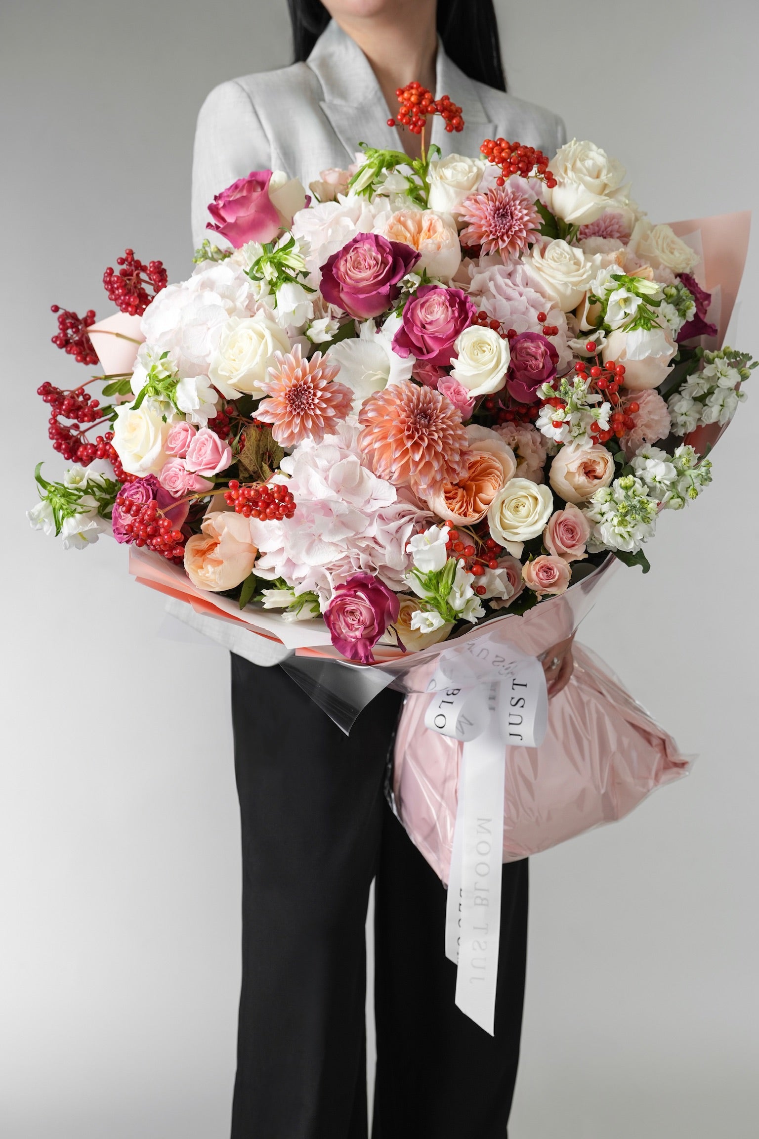 Blush Symphony bouquet with Juliet garden roses, dahlias, hydrangeas, lisianthus, and red Ilex berries