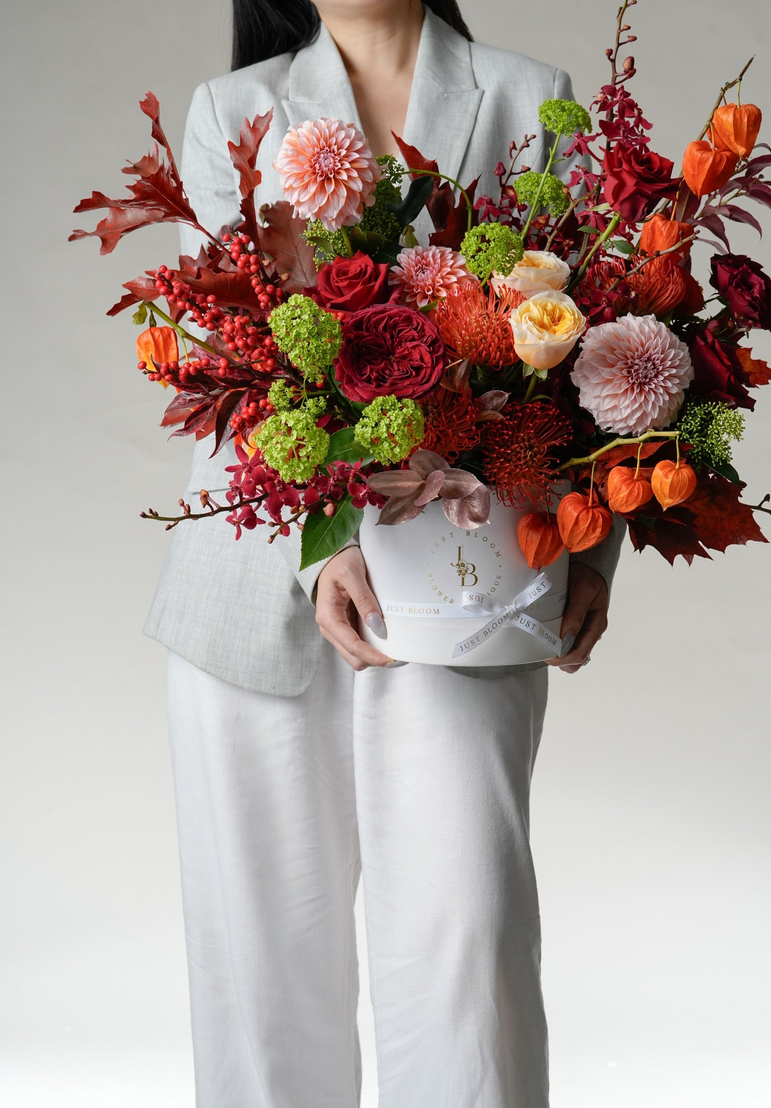 Ember Muse hatbox with red roses, dahlias, viburnum, and orange physalis