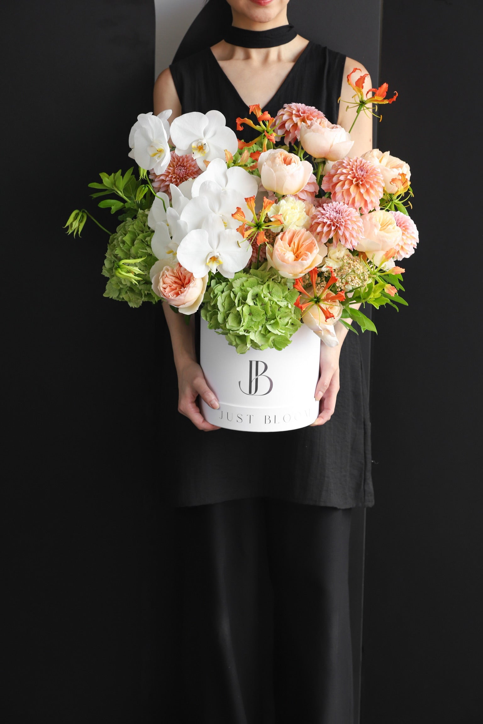 Model holding a large premium flower box arrangement in soft peach and white tones with Phalaenopsis Orchids and mixed seasonal blooms in a white Just Bloom hat box — Just Bloom Hong Kong