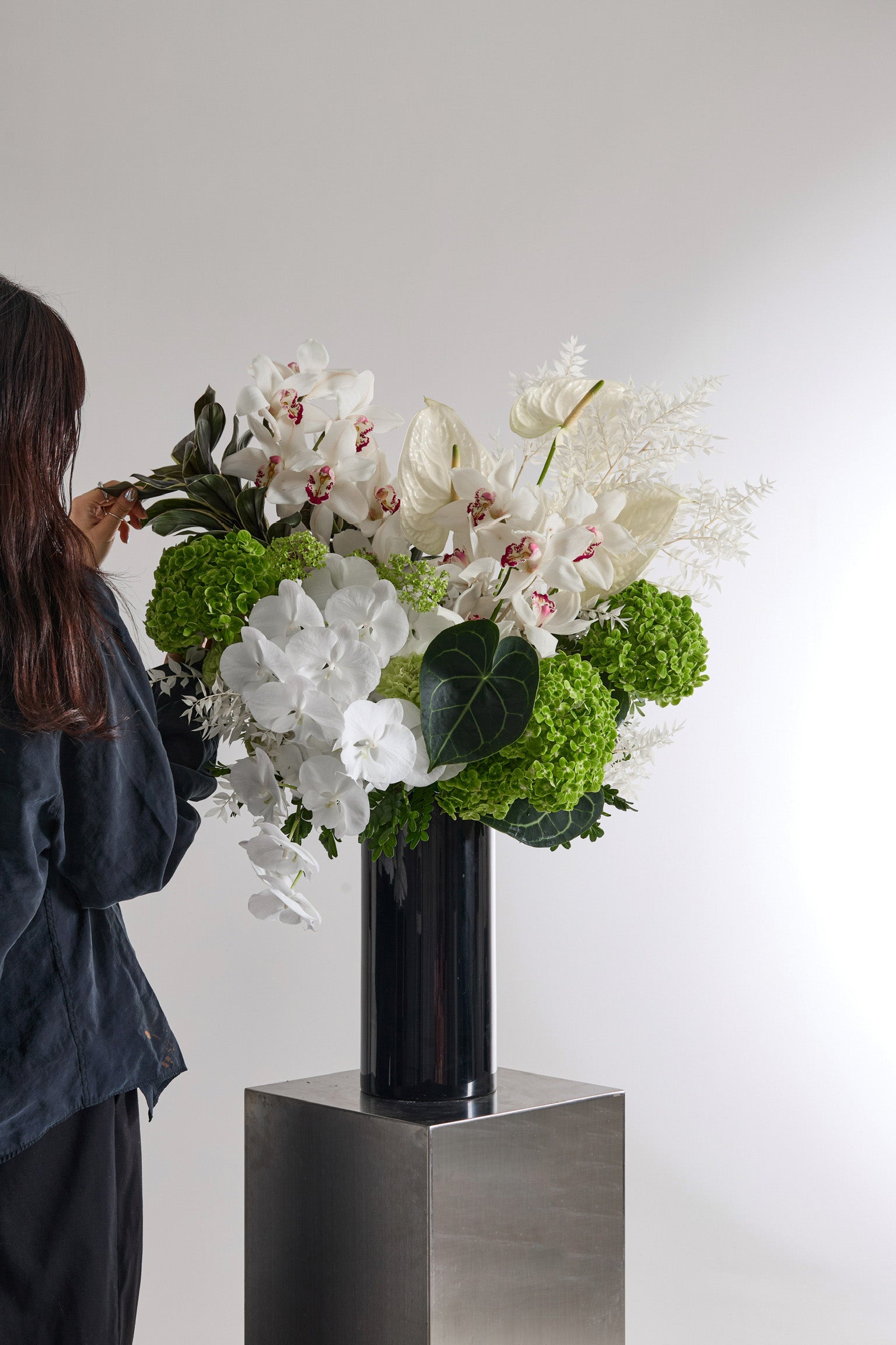 Ivory Verdure modern floral arrangement in dark ceramic vase with white orchids and green hydrangeas