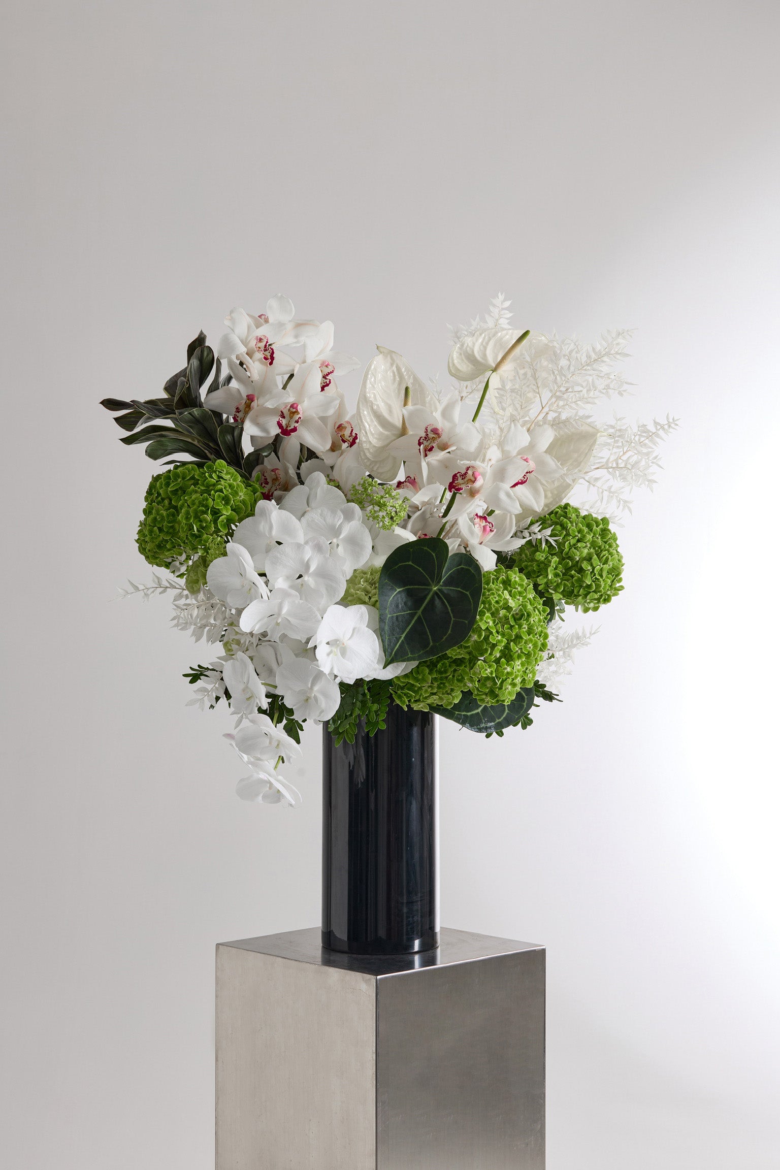 Ivory Verdure white and green vase arrangement with orchids hydrangeas and tropical foliage