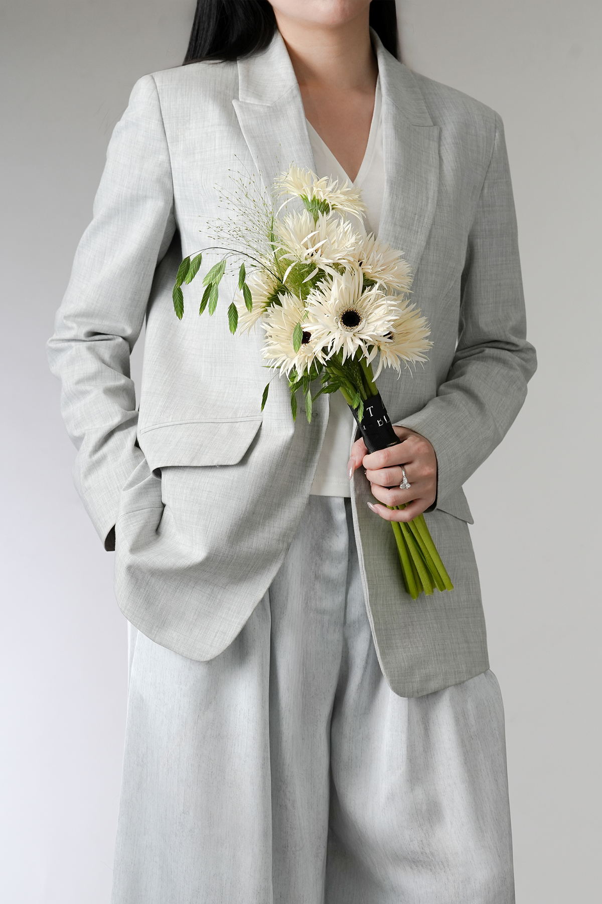 Ivory Whisper white gerbera bridal bouquet held by woman in grey suit