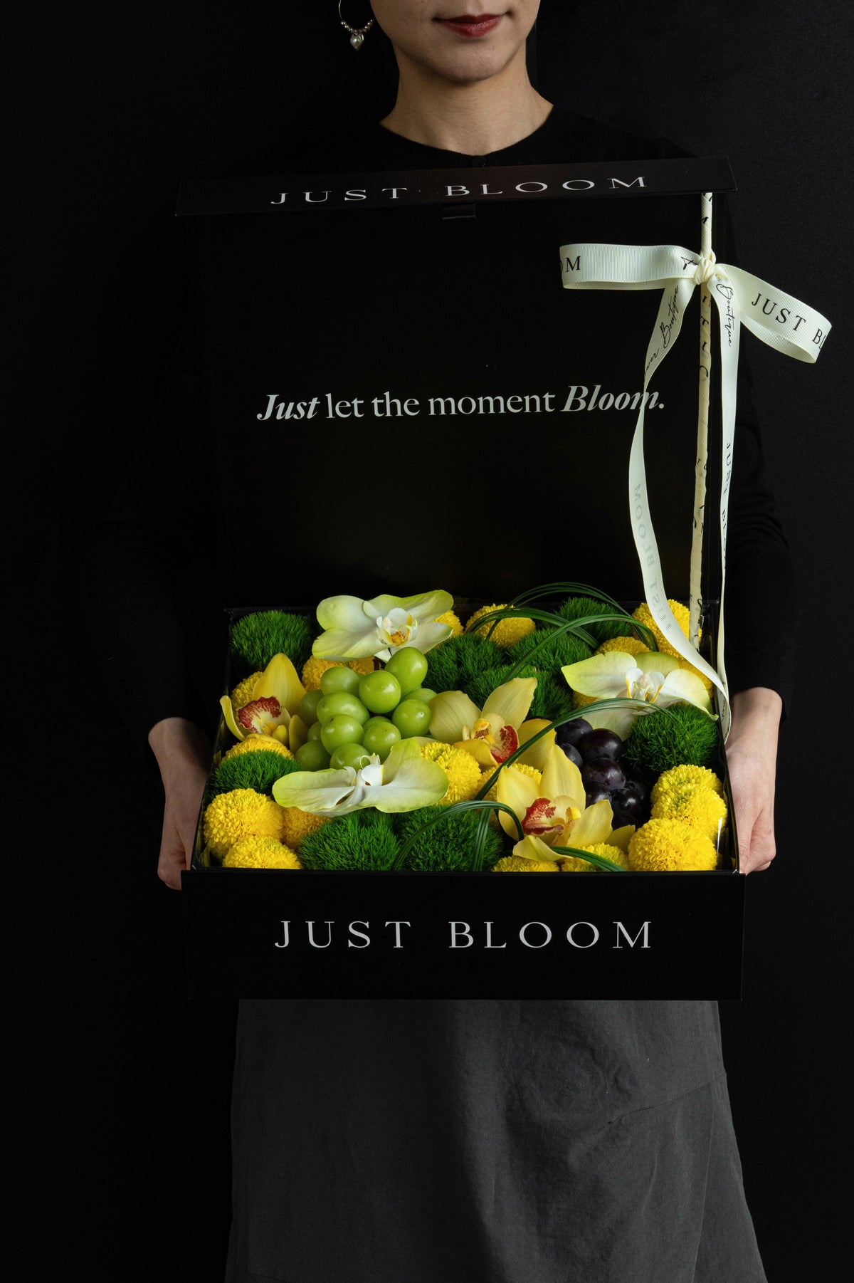 Model holding Just Bloom Jade Moon flower box with yellow and green florals and grapes — Just Bloom Hong Kong