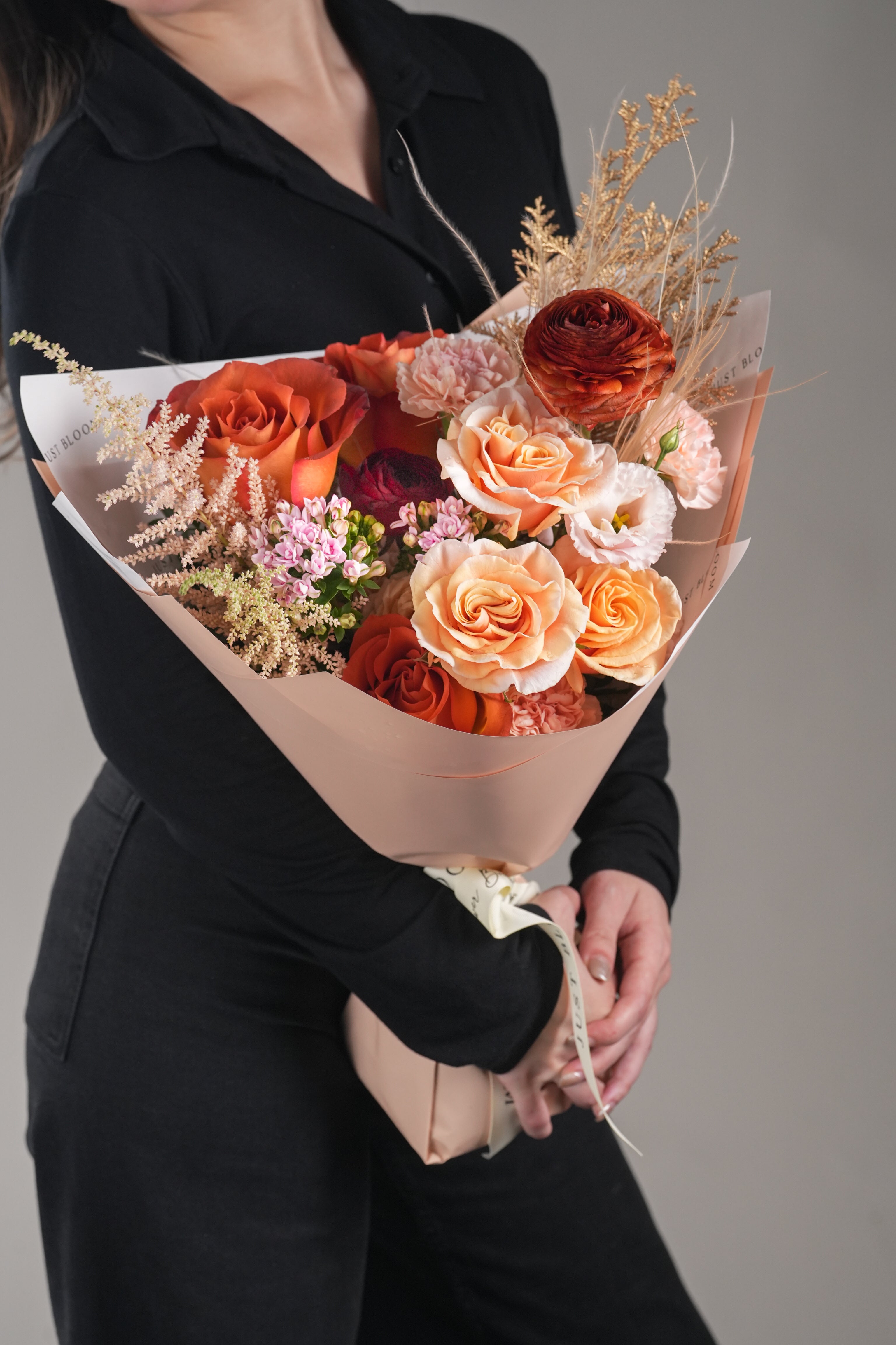 Just Bloom HK Gabriela bouquet held by model – hand-tied orange peach roses with ranunculus