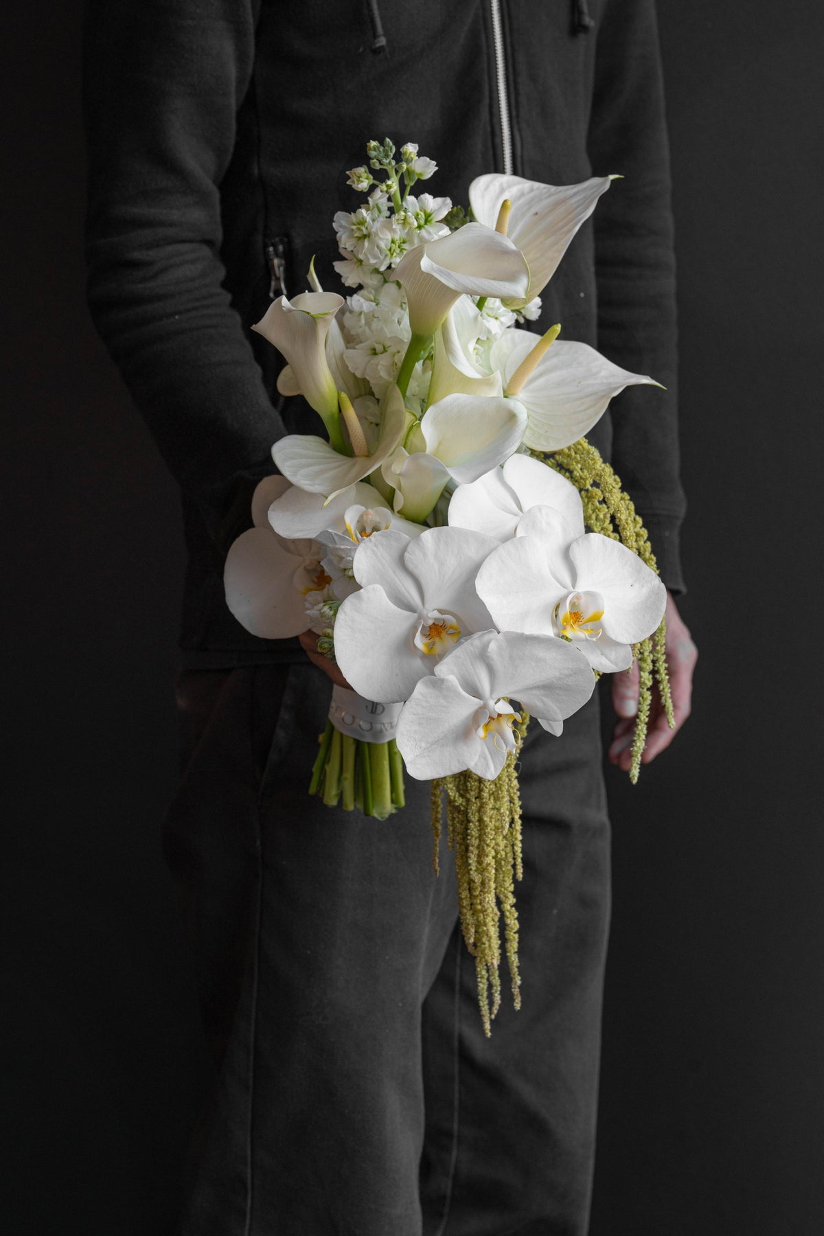 Model holding Now and Always bridal bouquet by Just Bloom Hong Kong, side profile view, showing the full cascading drop of trailing green against a dark background