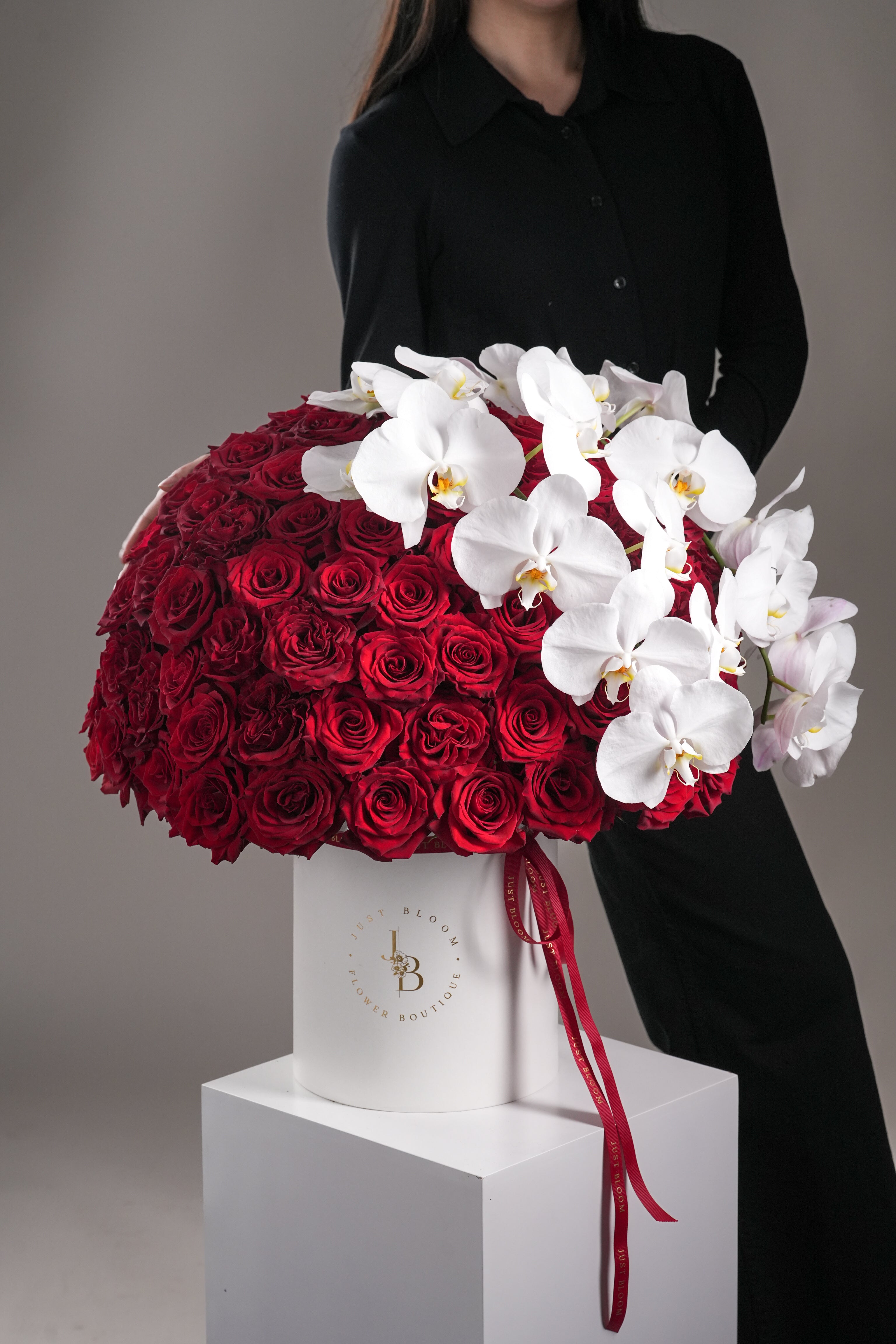 Model holding Faith red rose and orchid flower box by Just Bloom