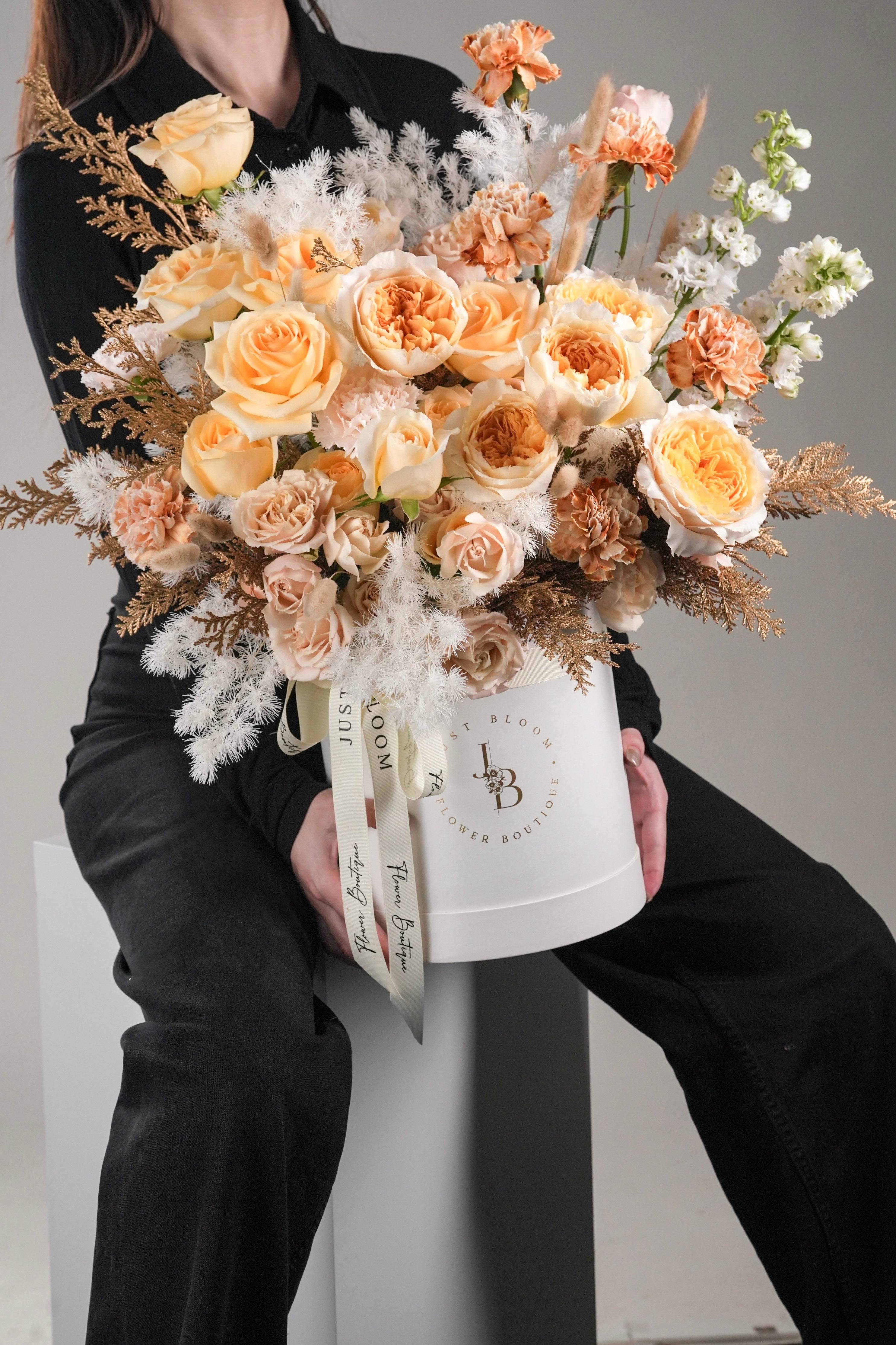 Kamiyah floral arrangement featuring warm-toned roses, preserved white textures, and gold leaves