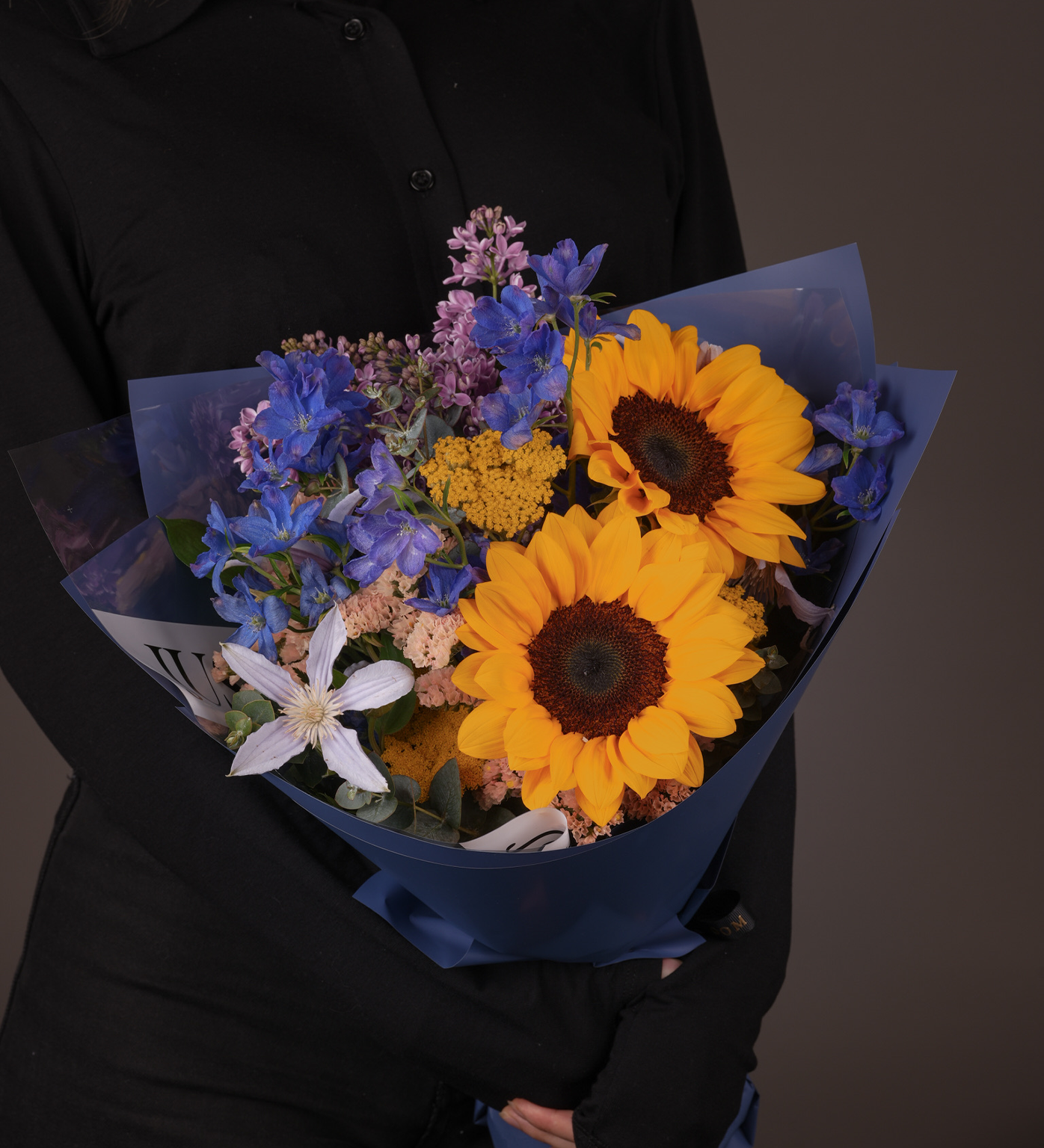 Close-up view of Kelsey bouquet showing sunflowers, clematis, and colorful filler flowers arrangement