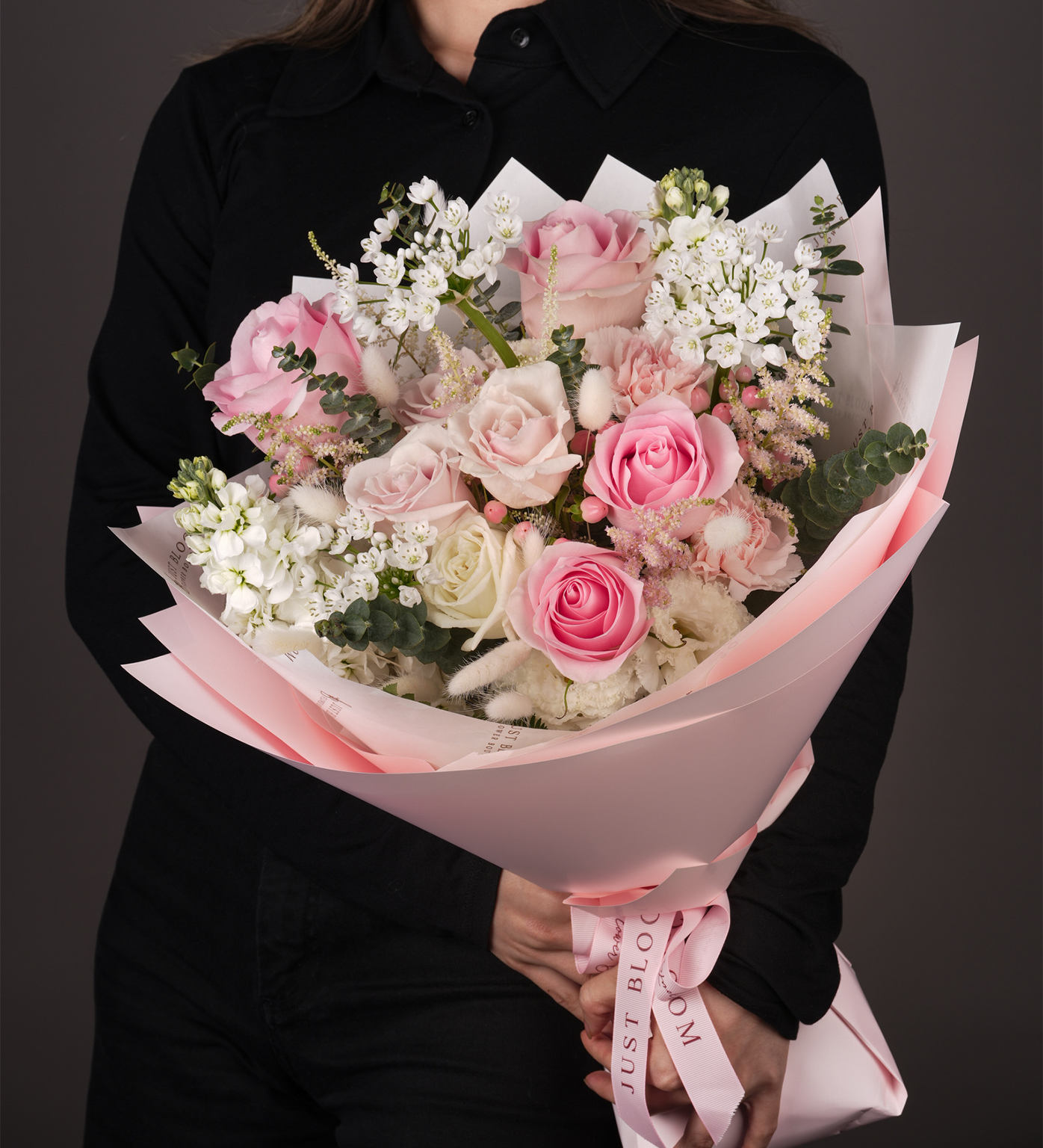 Kennedi pink and white rose mixed bouquet with Dutch florals held by woman in black shirt with pink wrapping