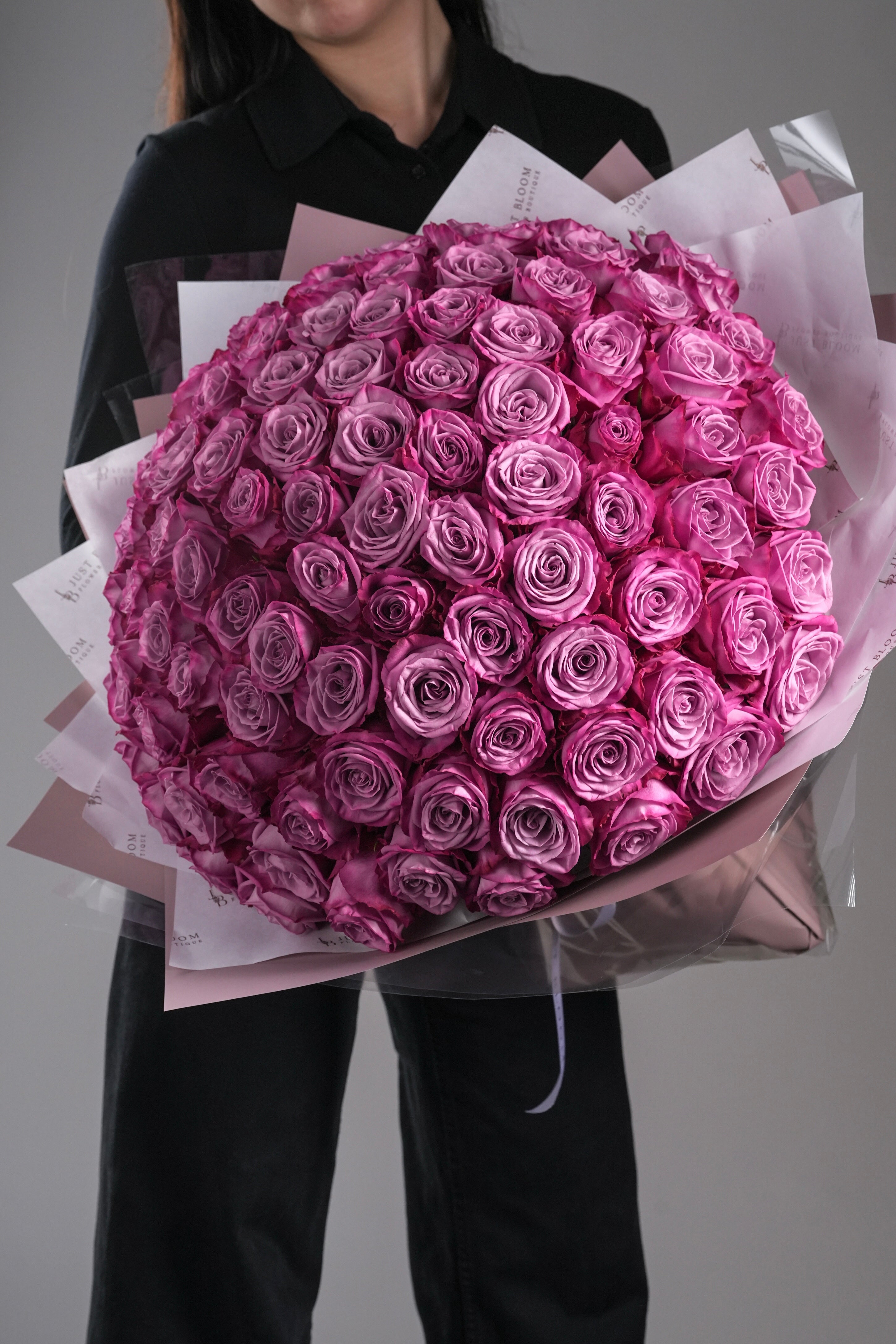 Kinley luxury large purple rose bouquet with dozens of Ecuadorian roses held by woman in black outfit