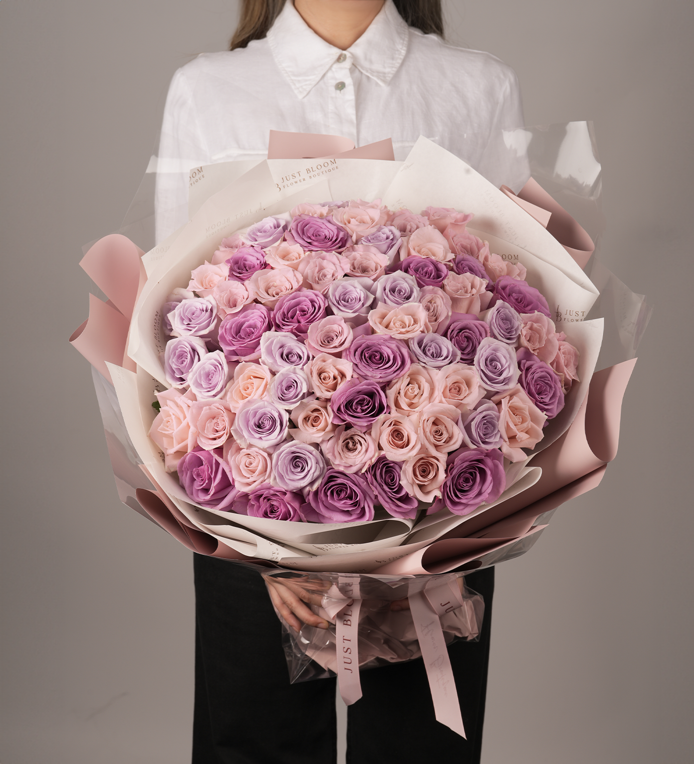 Kora luxury large purple pink rose bouquet with dozens of Ecuadorian roses held by woman in white shirt