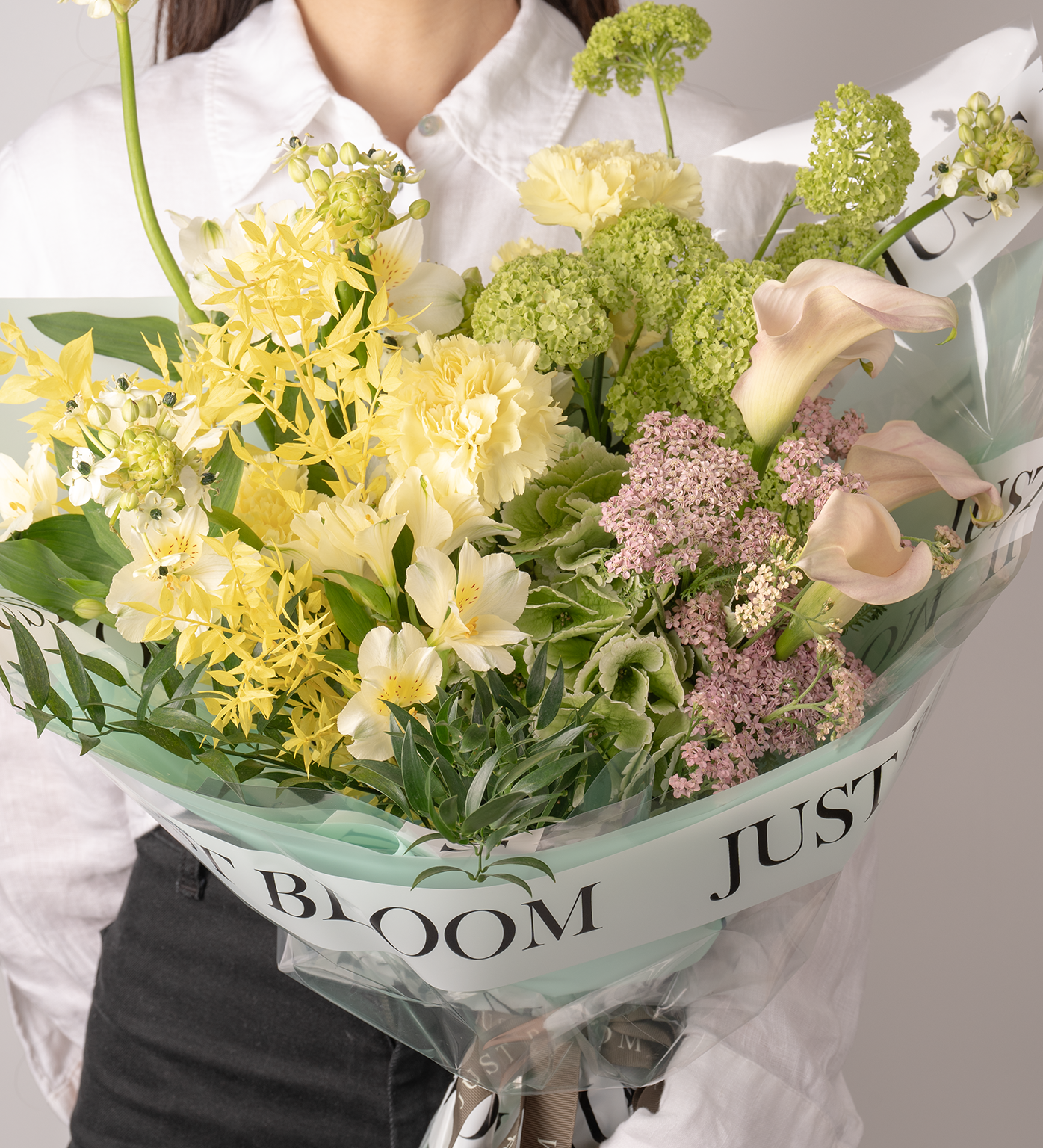 Close-up view of Lana bouquet showing calla lilies, yellow carnations, and green hydrangeas arrangement