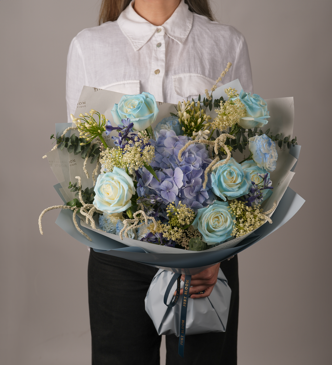 Legacy blue rose and hydrangea premium bouquet with Dutch florals held by woman in white shirt
