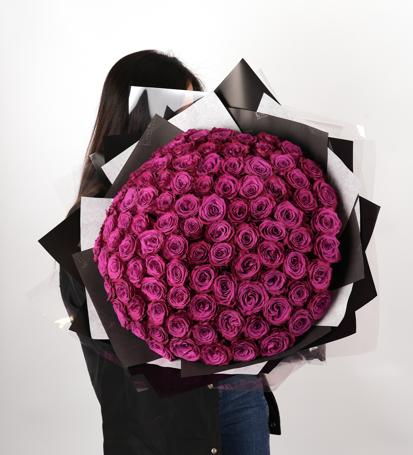 Woman holding Leia 99 fuchsia rose bouquet showing impressive scale and dramatic presentation