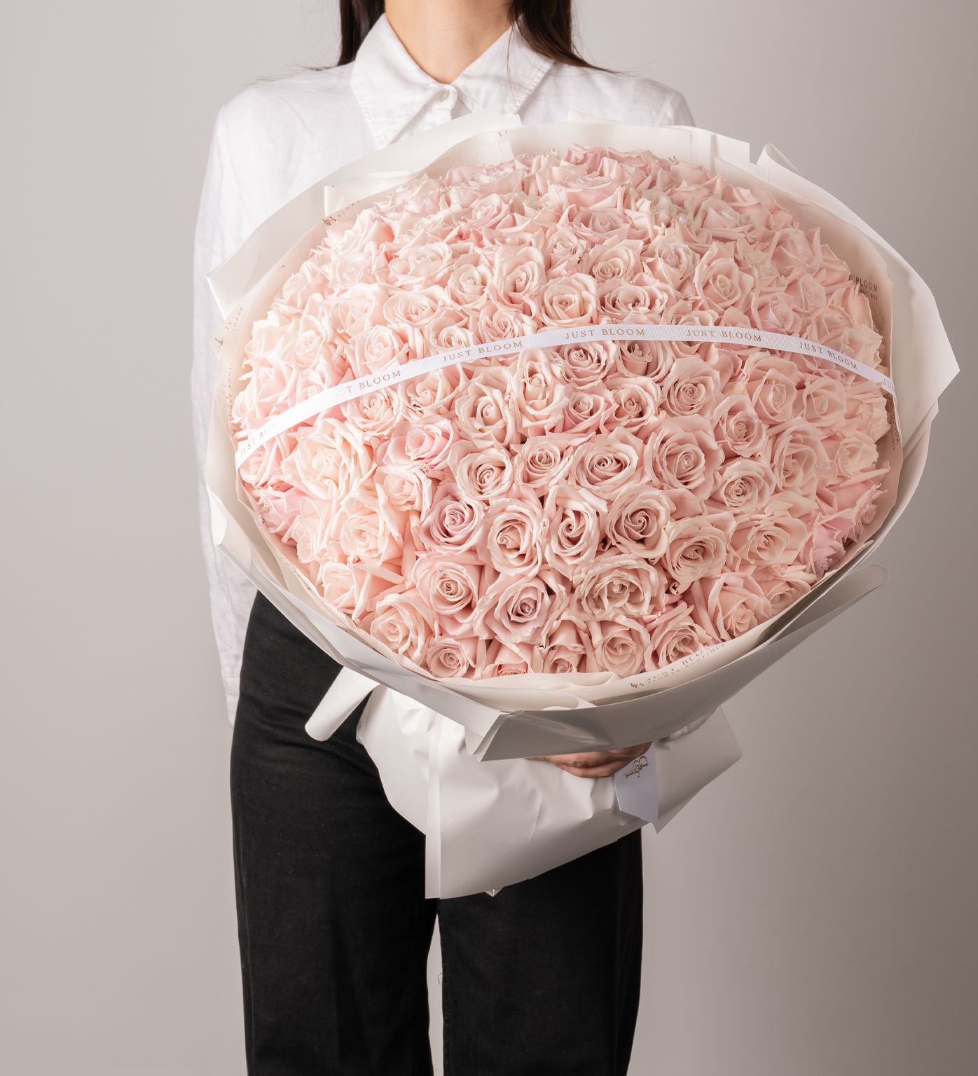 Lennon luxury large pink rose bouquet held by woman in white shirt with elegant white wrapping