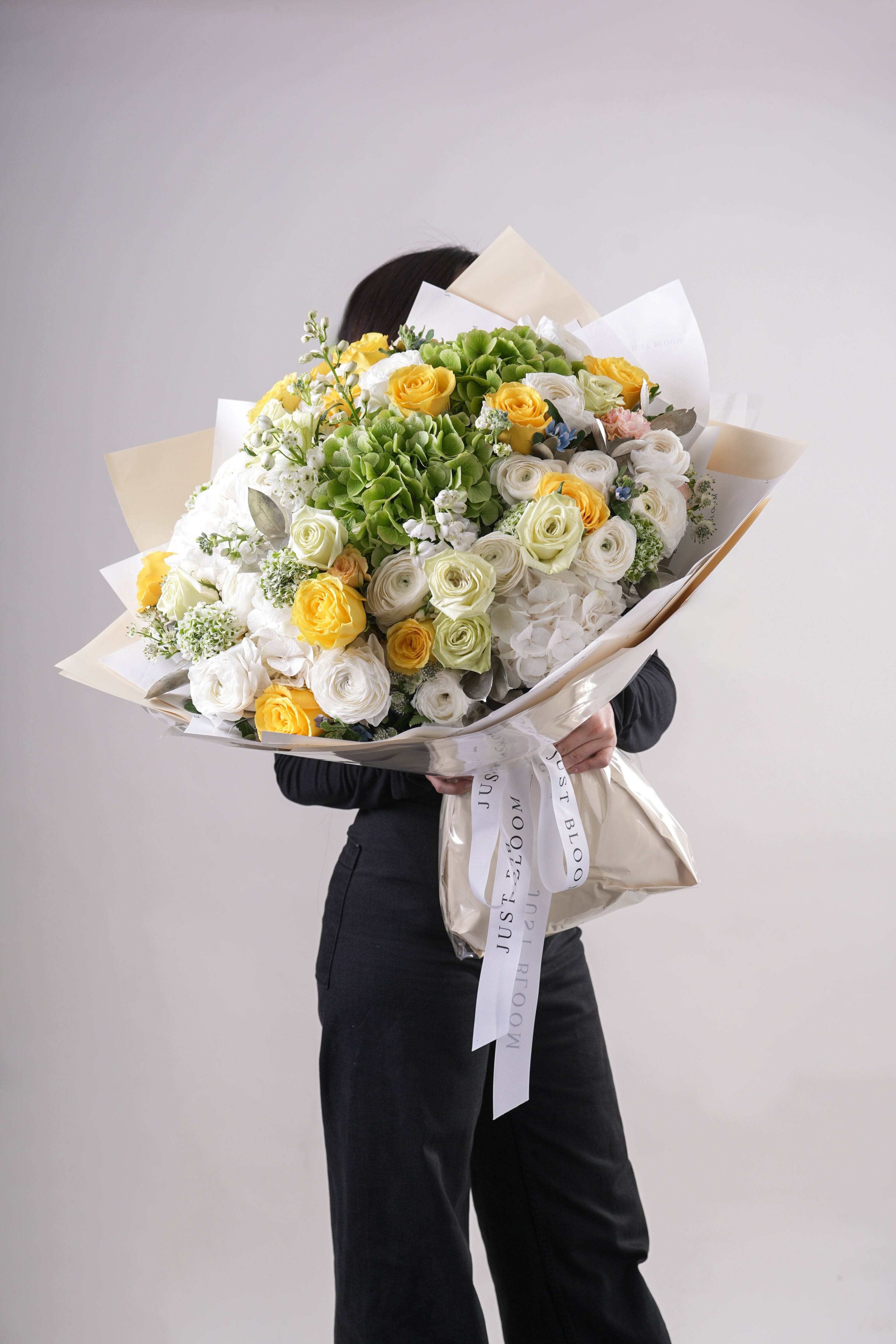 Side view of Lilly bouquet showing yellow roses, green hydrangeas, and white ranunculus arrangement