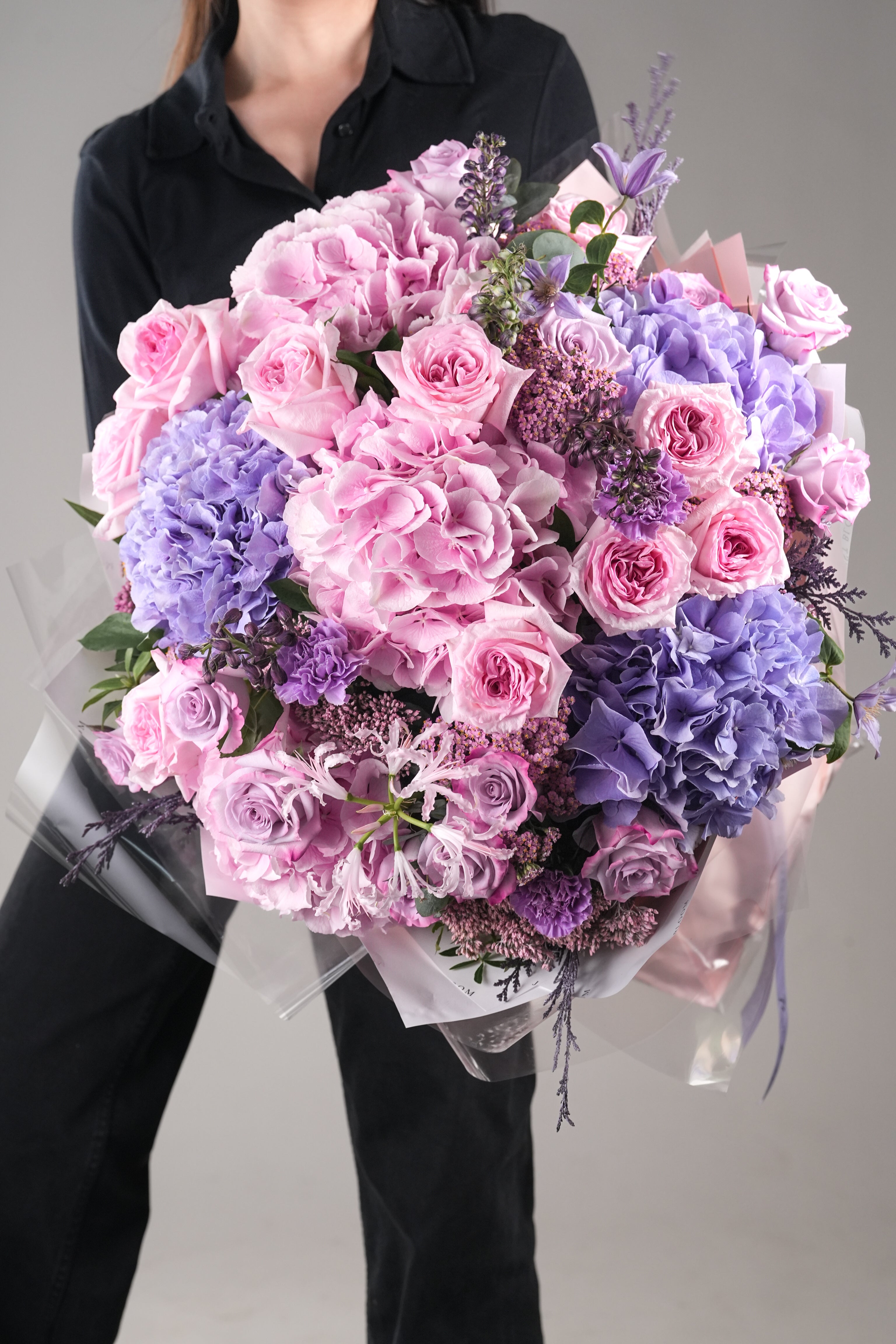 Close-up view of Livia bouquet showing pink garden roses, purple hydrangeas, and delphinium arrangement