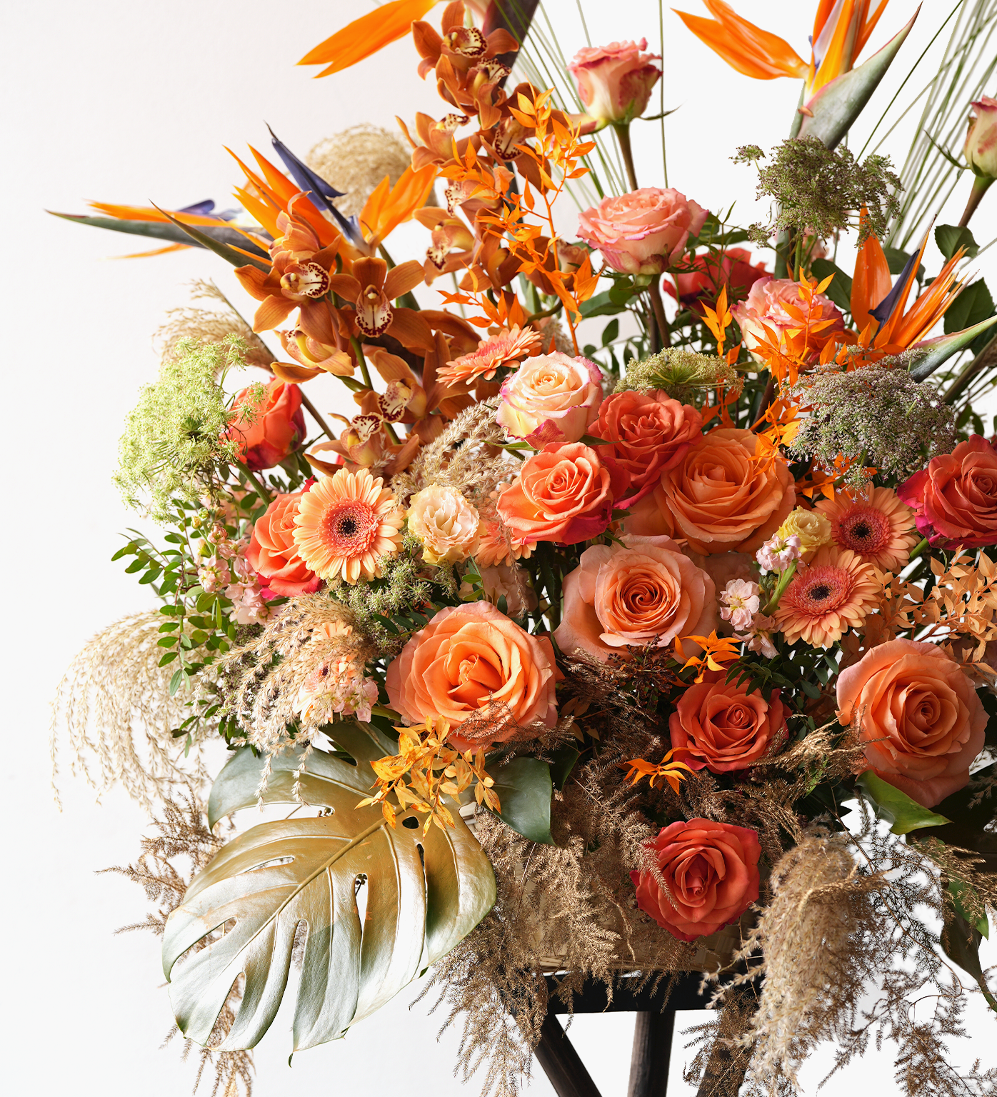 Close-up view of Lucille showing bird of paradise, orange roses, and tropical greenery arrangement