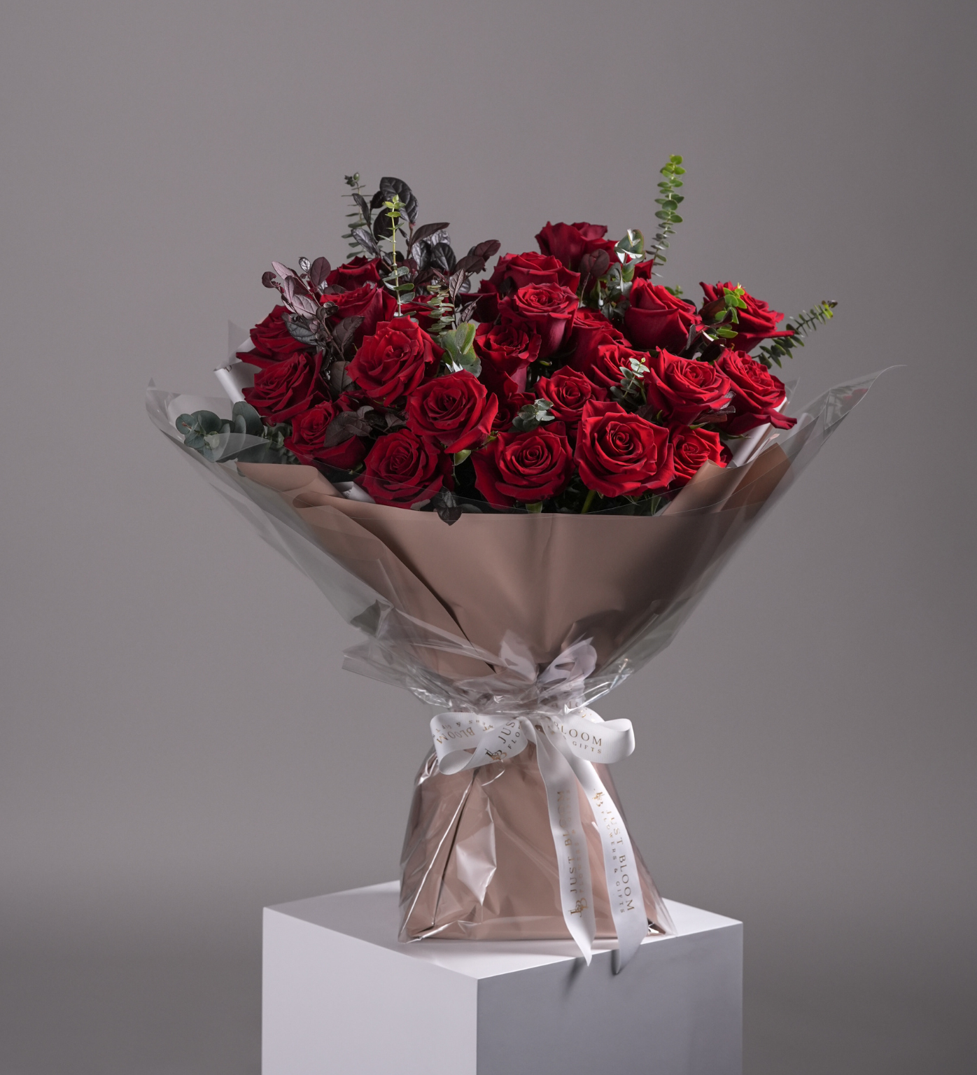 Close-up of Lyla bouquet showing red roses and eucalyptus in elegant champagne wrapping