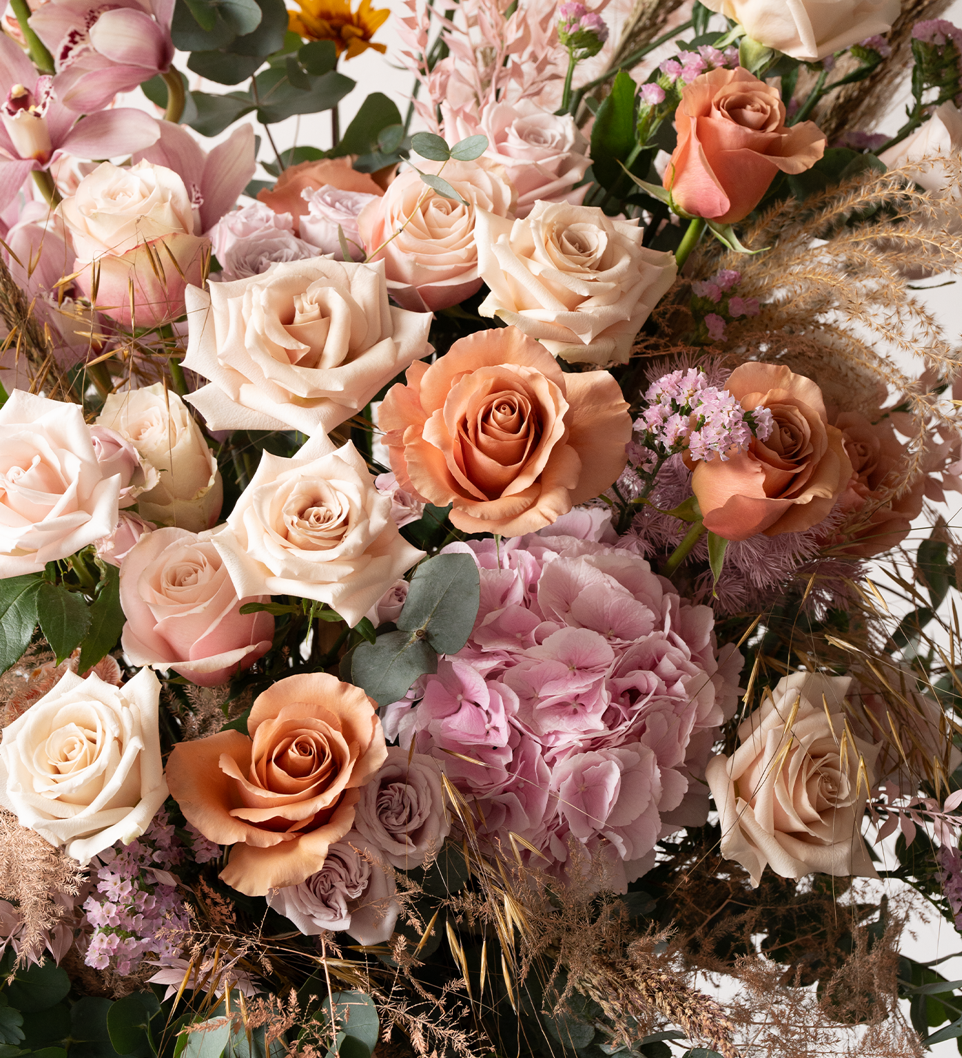 Close-up of Maci flower stand showing roses, hydrangeas, cymbidiums, and delicate fillers in blush and peach tones