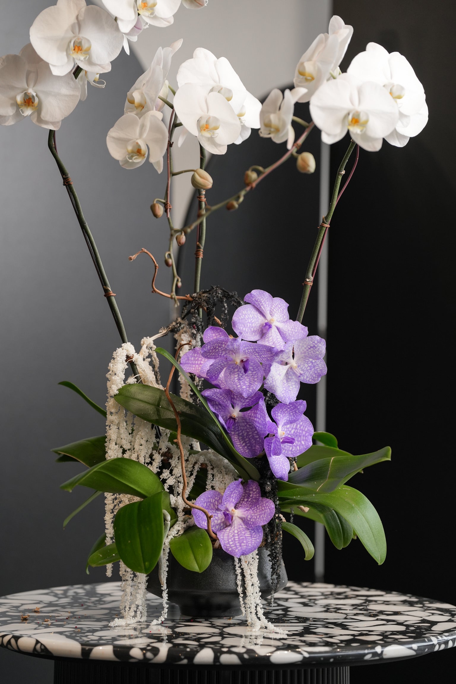 Close-up of Mae arrangement showing purple orchids, white orchids, and cascading fillers