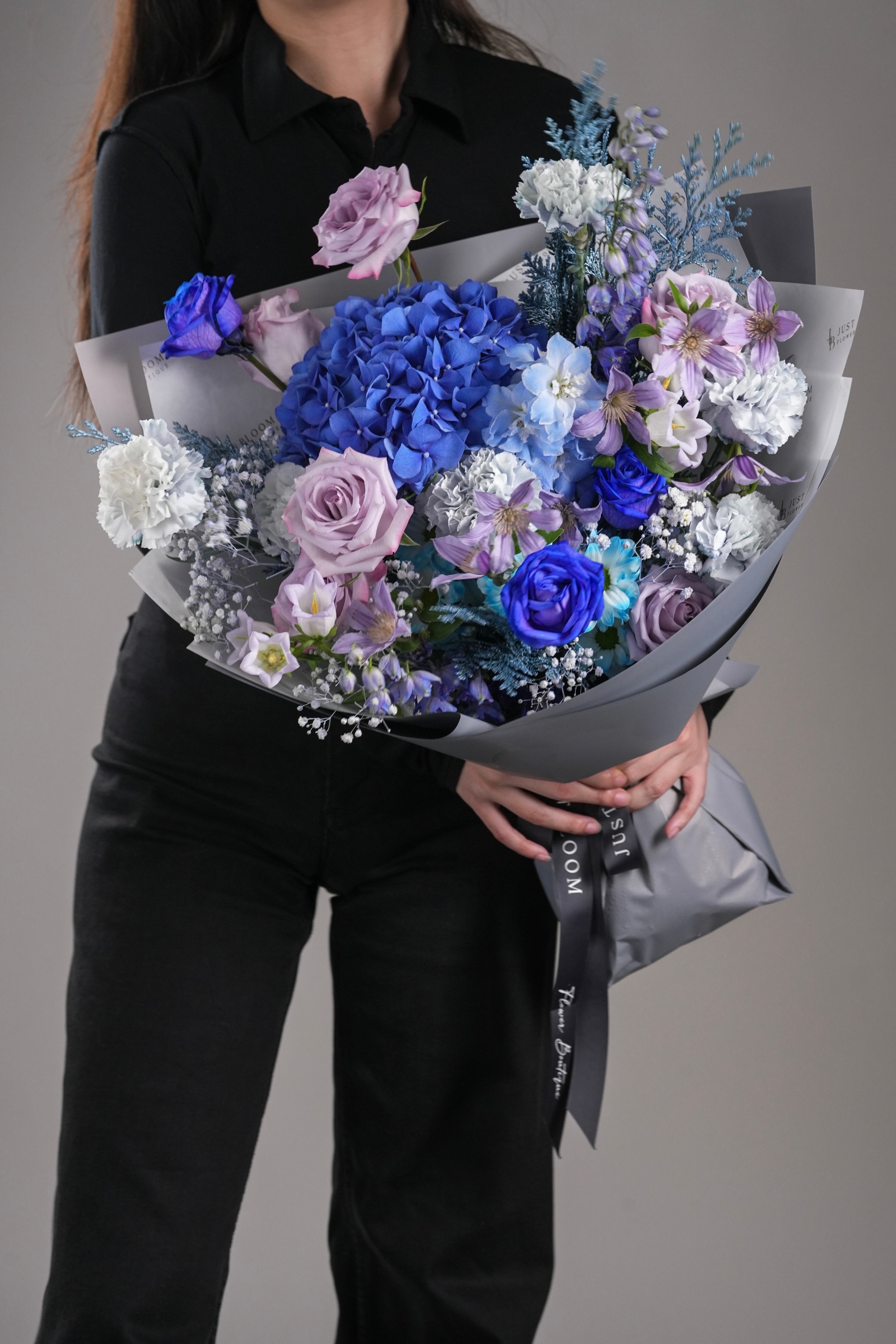 Close-up of Maeve bouquet showing blue hydrangeas, purple roses, and carnations in a romantic colour palette