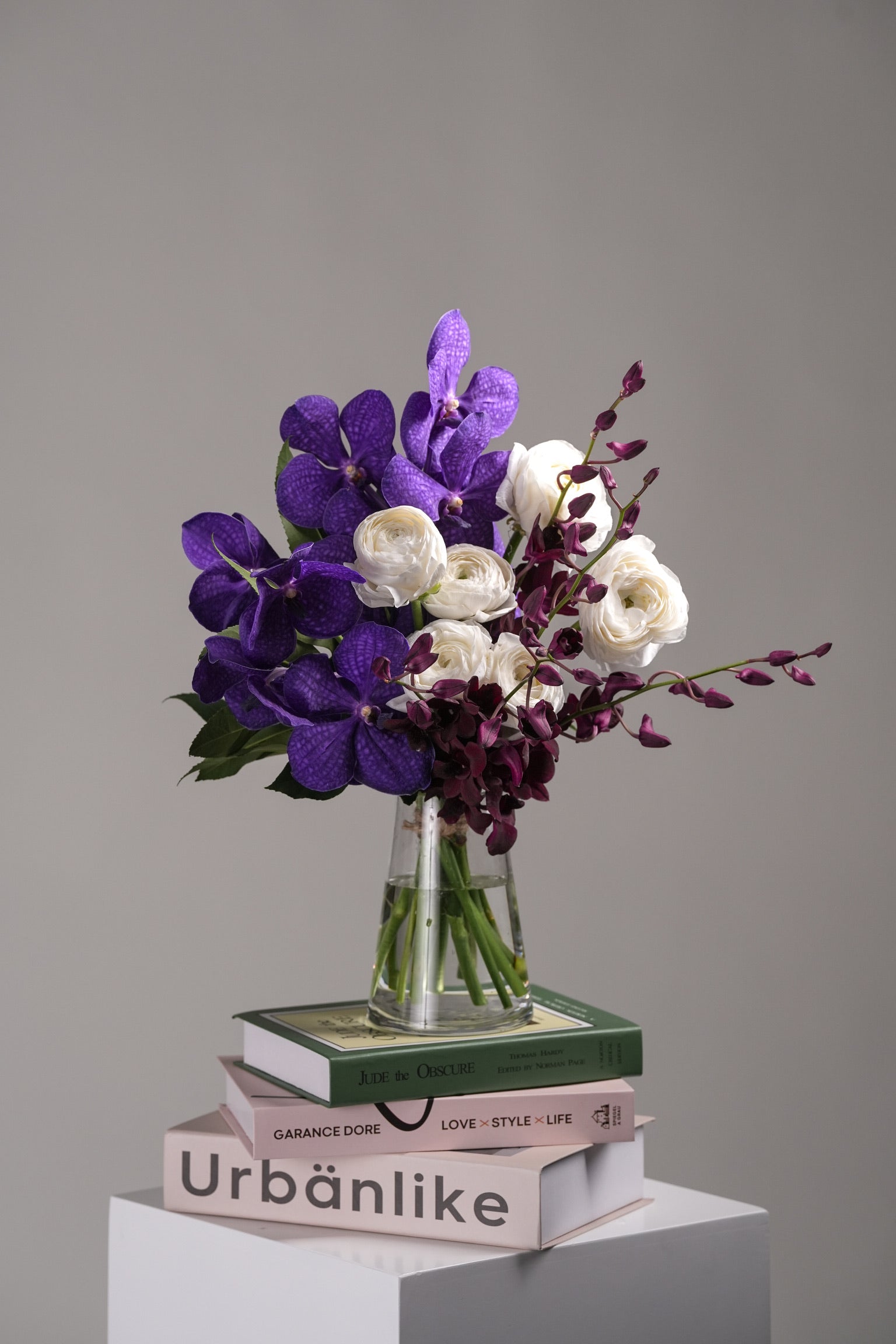 Mallory vase arrangement with purple ranunculus, magenta flowers, and greenery in a clear glass vase