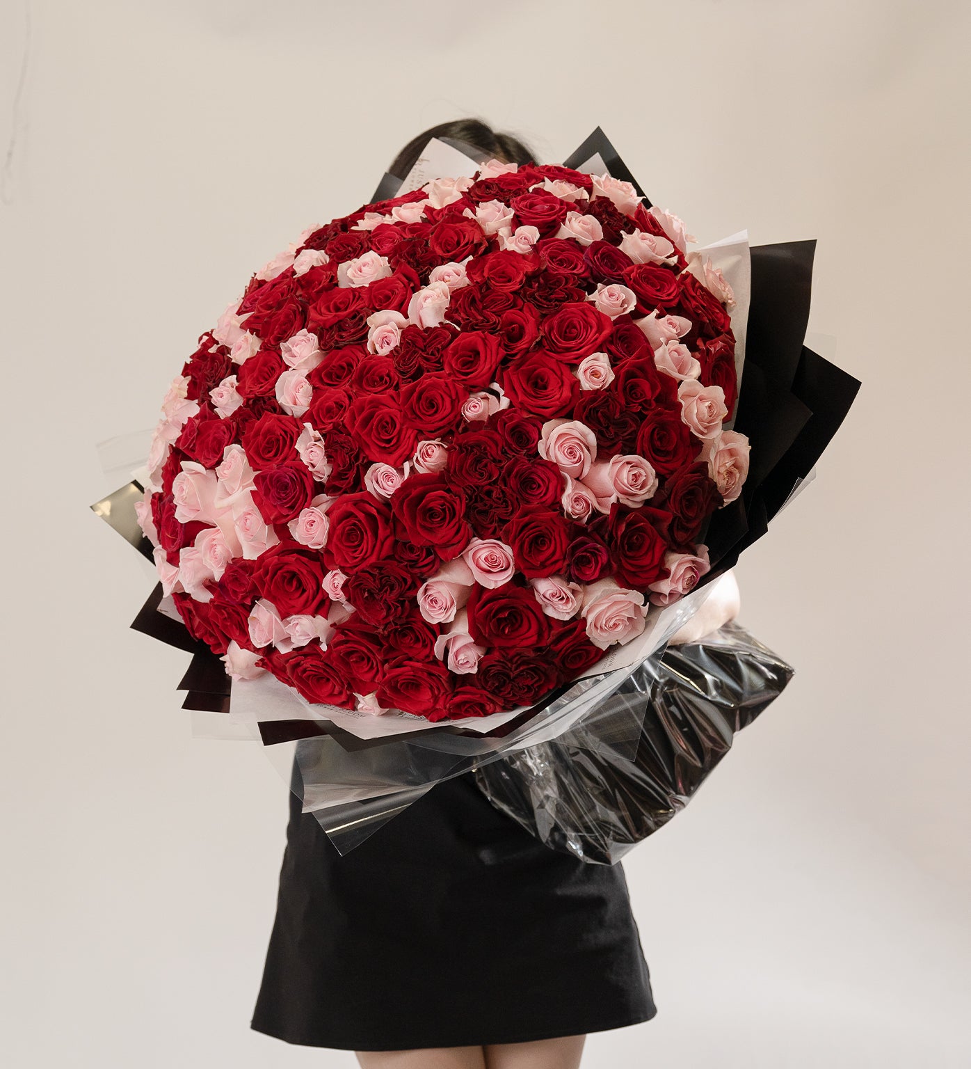 Woman holding Marisol bouquet with vibrant red and pink Ecuadorian roses