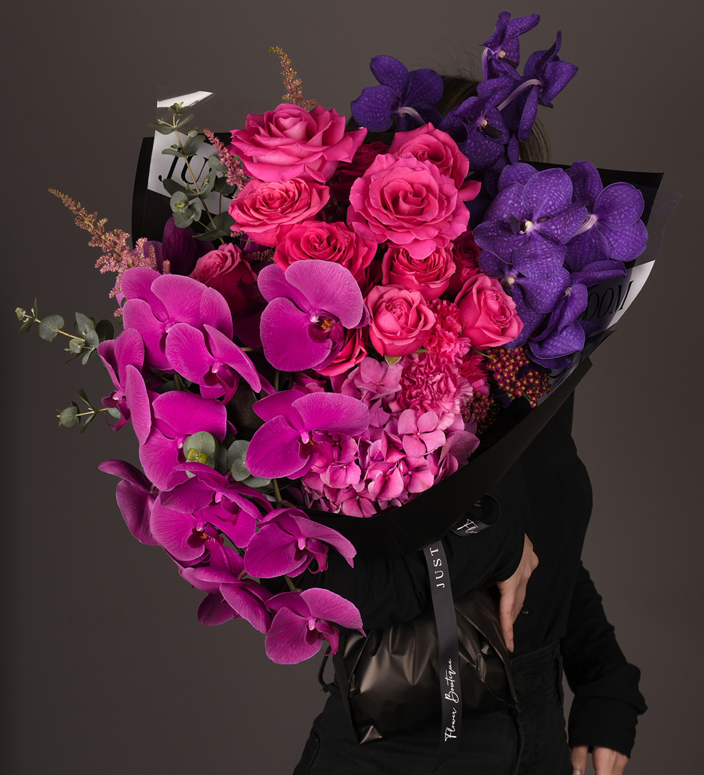 Monroe bouquet being held, featuring vibrant purple and pink blooms with eucalyptus