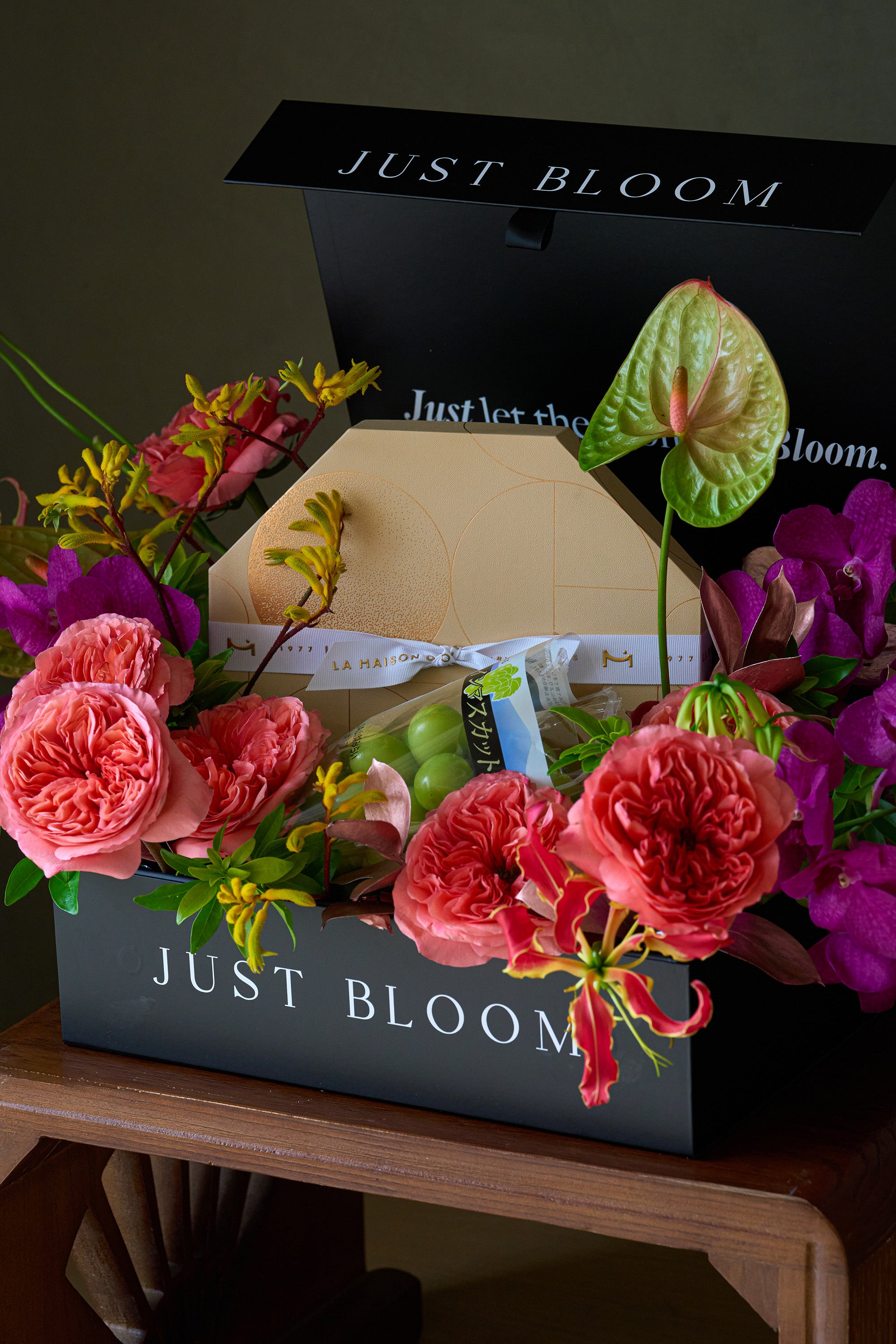Full view of Just Bloom flower box with chocolate and grape gift set displayed on a wooden side table — Just Bloom Hong Kong