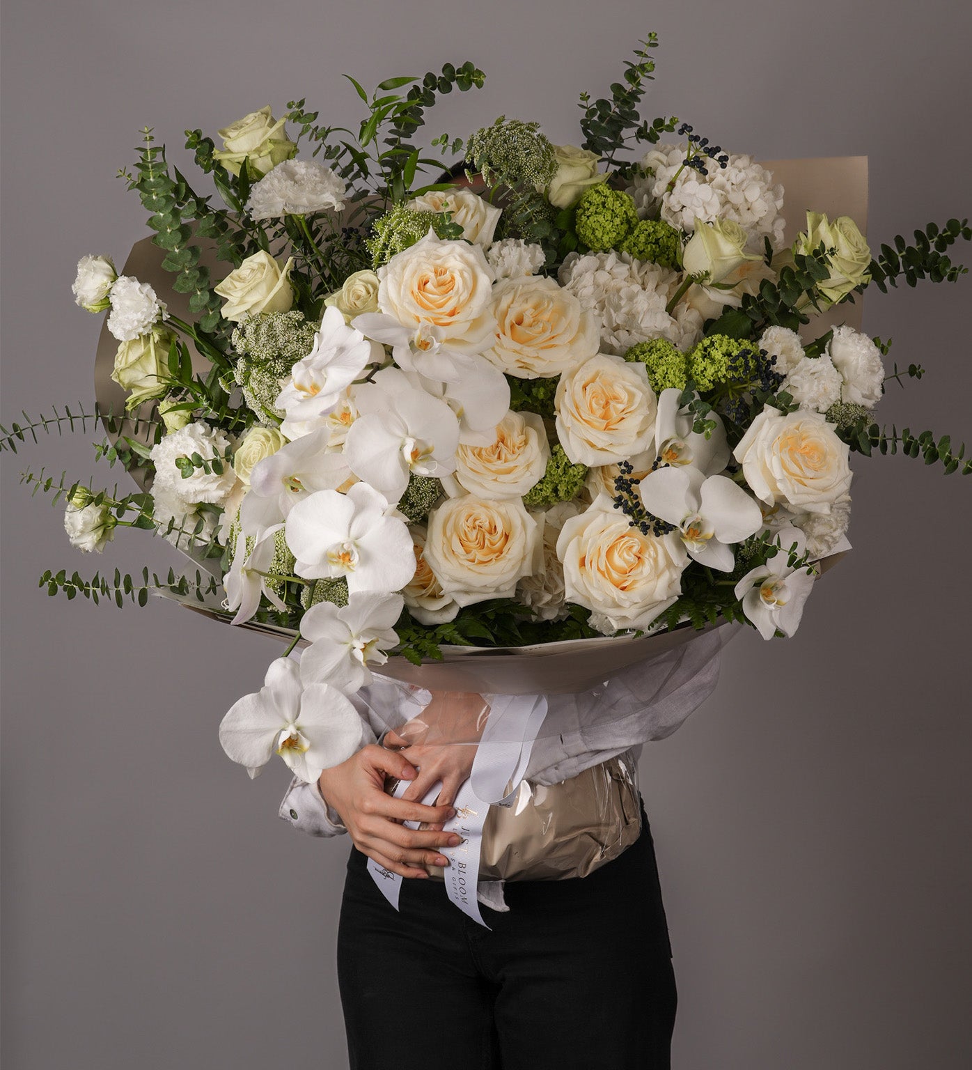 Nadia grand bouquet with cream roses, white phalaenopsis orchids, and greenery, side view