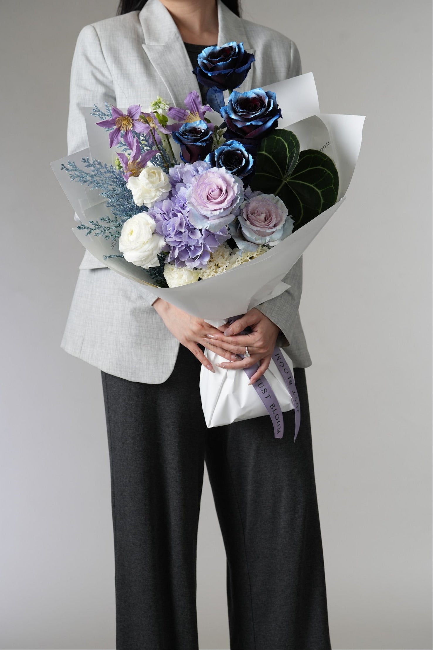 Noctis bouquet featuring midnight blue roses and white ranunculus with cool-toned foliage