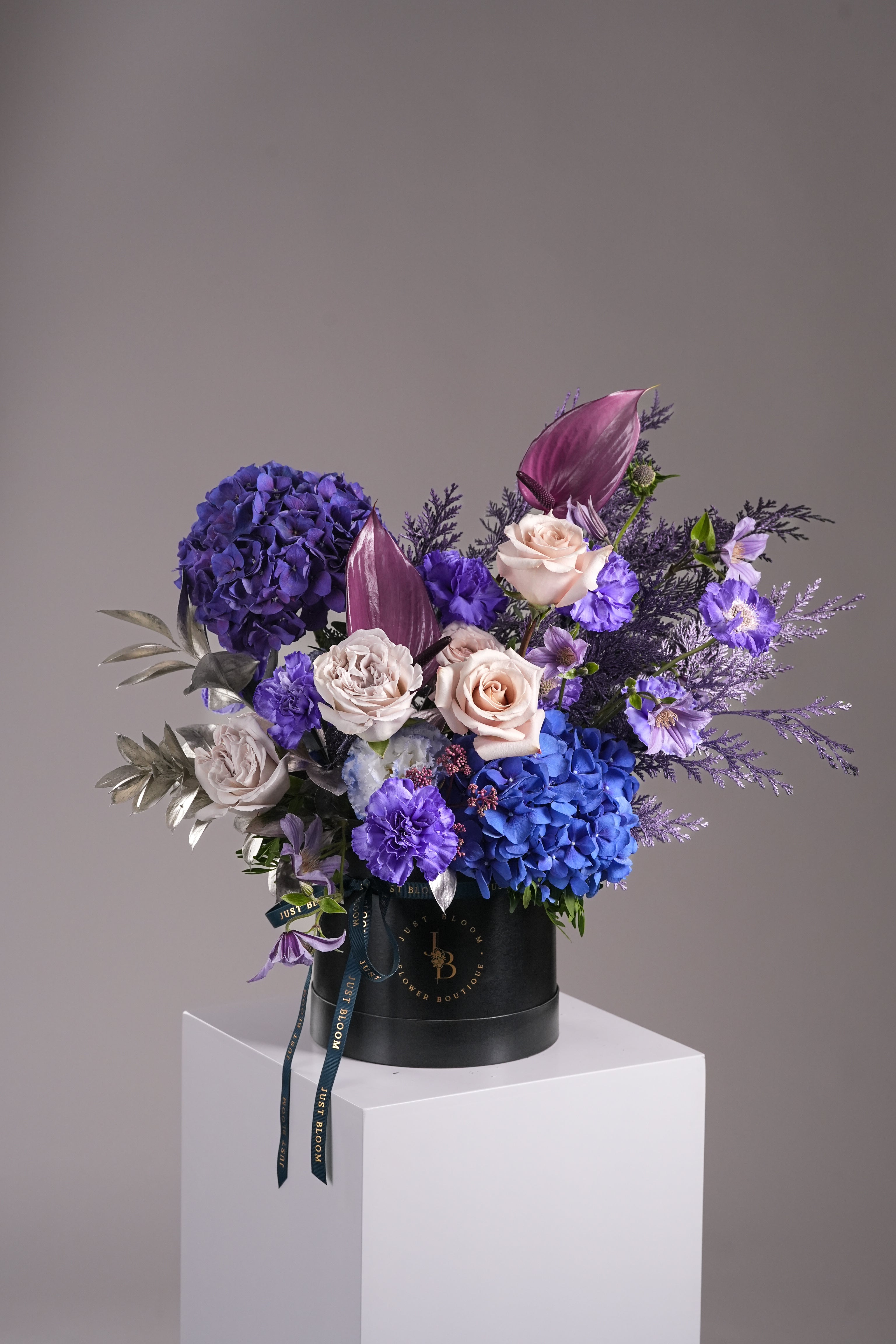 Noel hatbox with purple hydrangeas, grey roses and dyed leaves