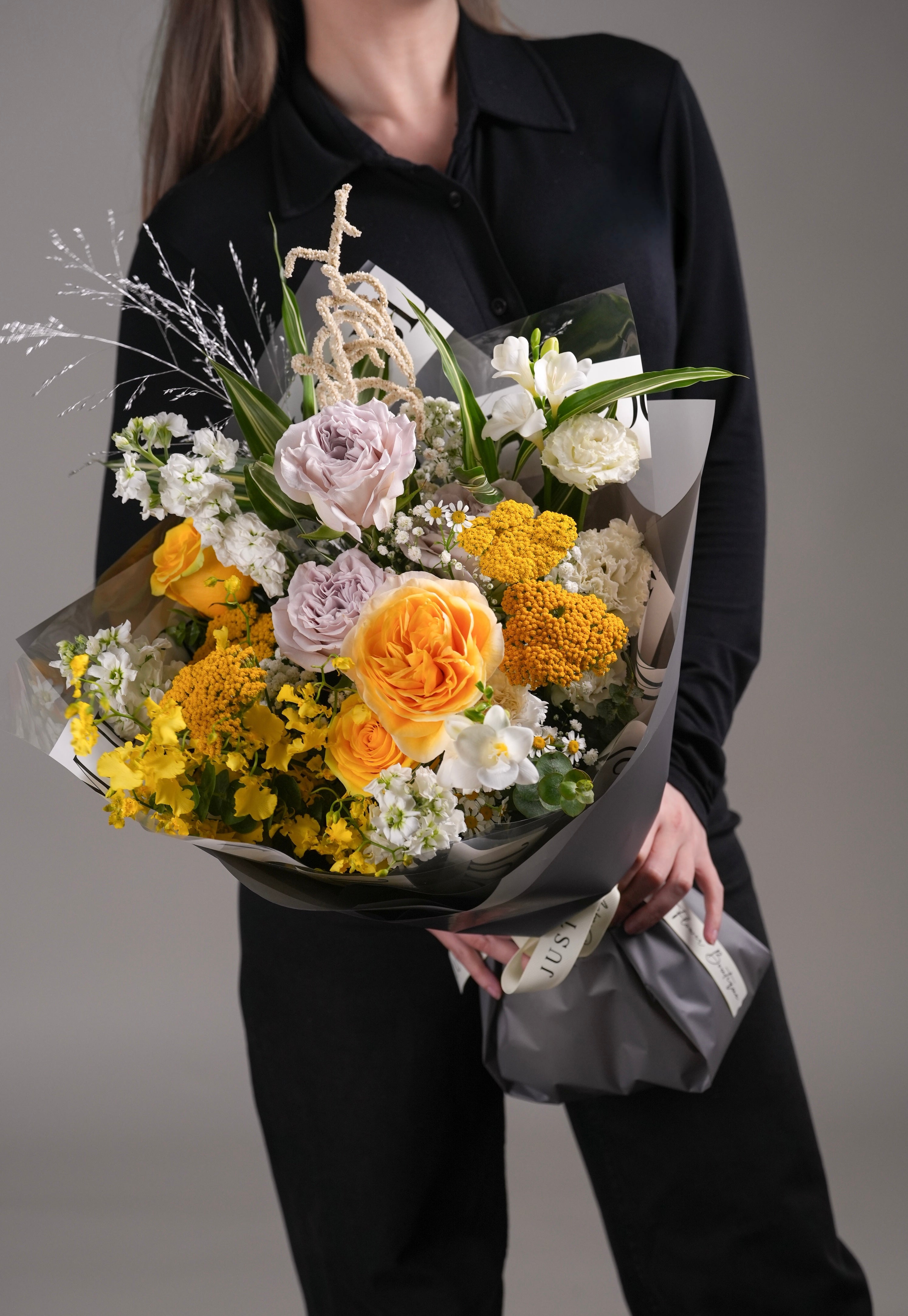 Phoenix bouquet with vibrant yellow flowers wrapped in grey paper and white ribbon