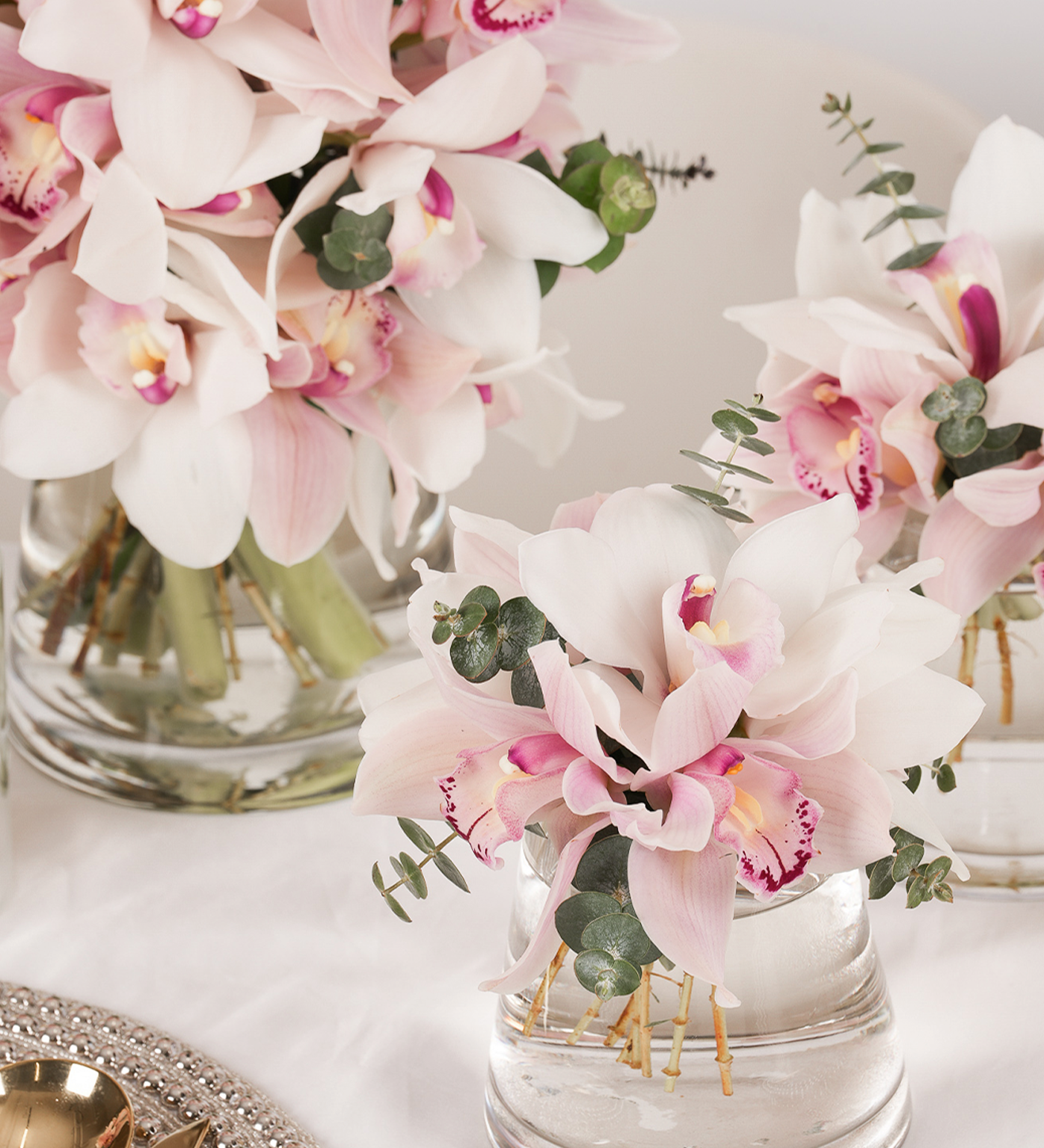 Pink Paradise mini table arrangement featuring blush cymbidiums and eucalyptus