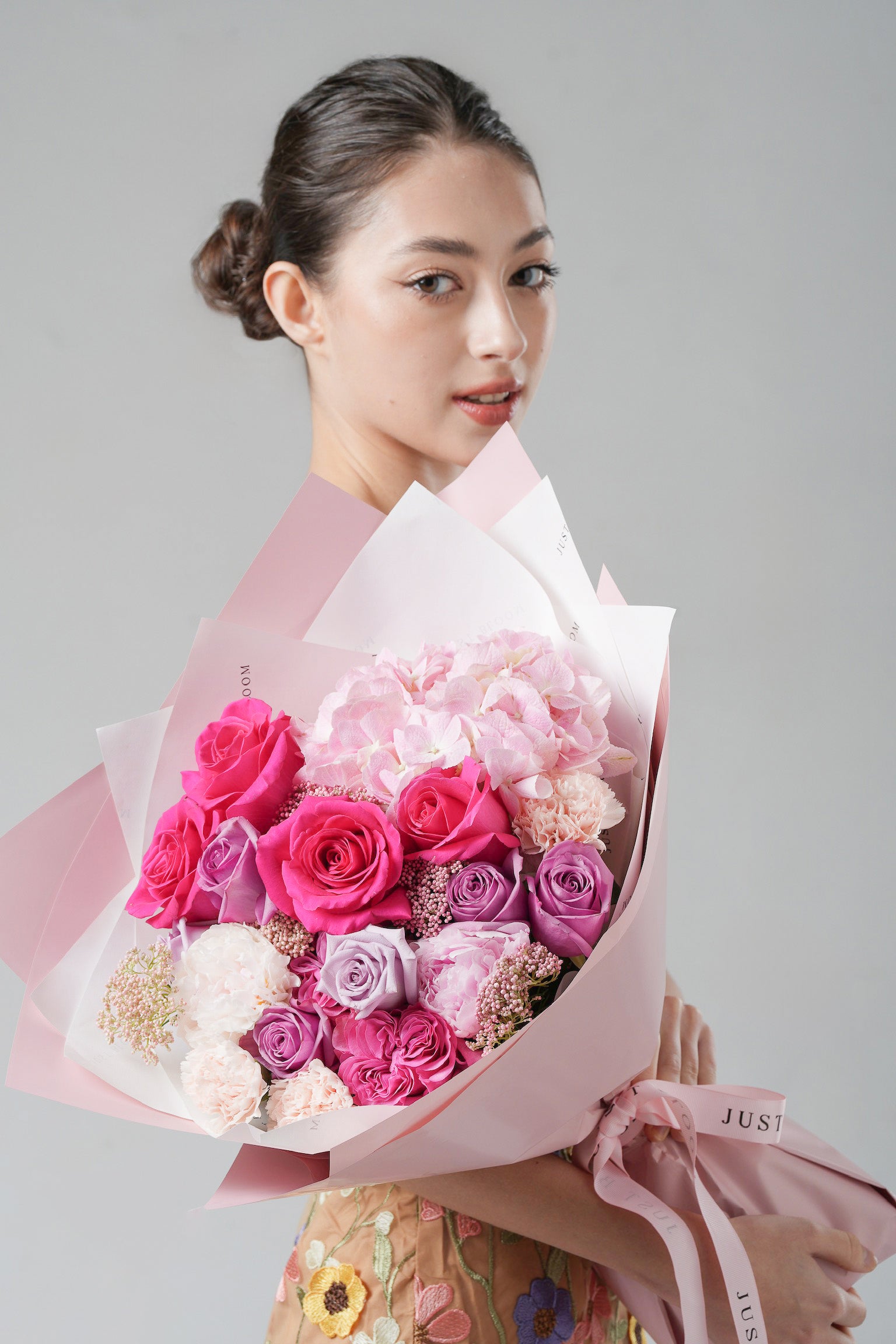 A bold and elegant bouquet featuring fuchsia roses, lavender garden roses, pink hydrangeas, and peonies in soft pastel tones.