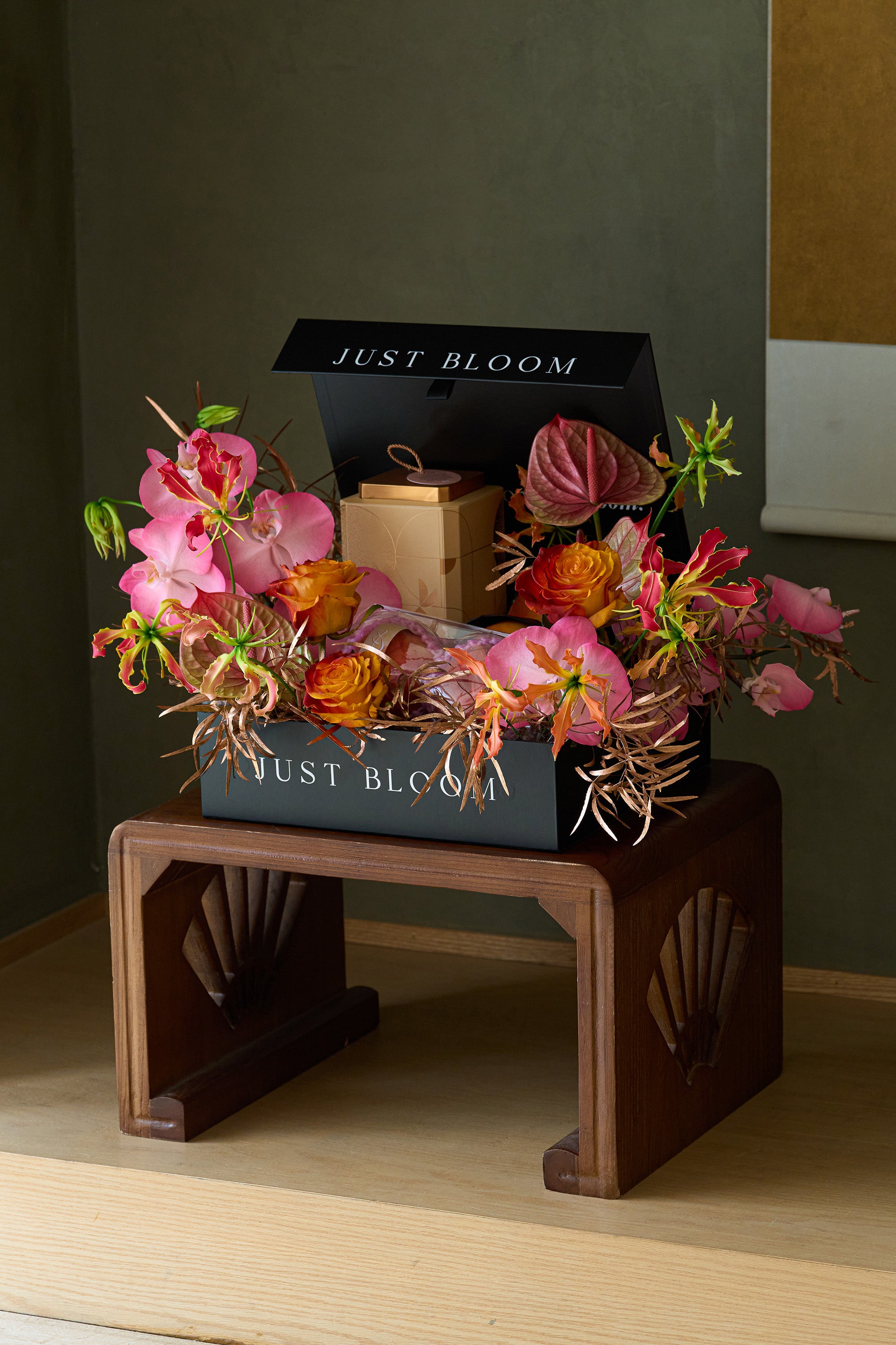 Just Bloom Radiant Reunion flower box with pink orchids, orange roses and Radiant Moon Delight chocolate gift box on a wooden stand — Just Bloom Hong Kong