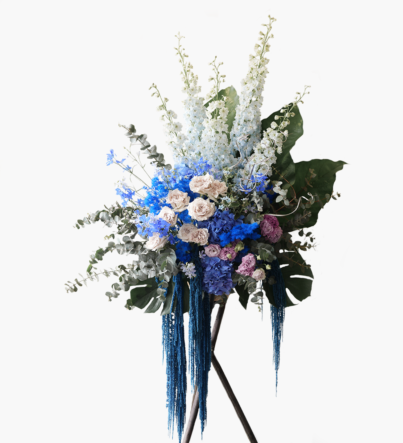 Raegan flower stand with blue hydrangeas, blush roses, and delphiniums cascading with eucalyptus