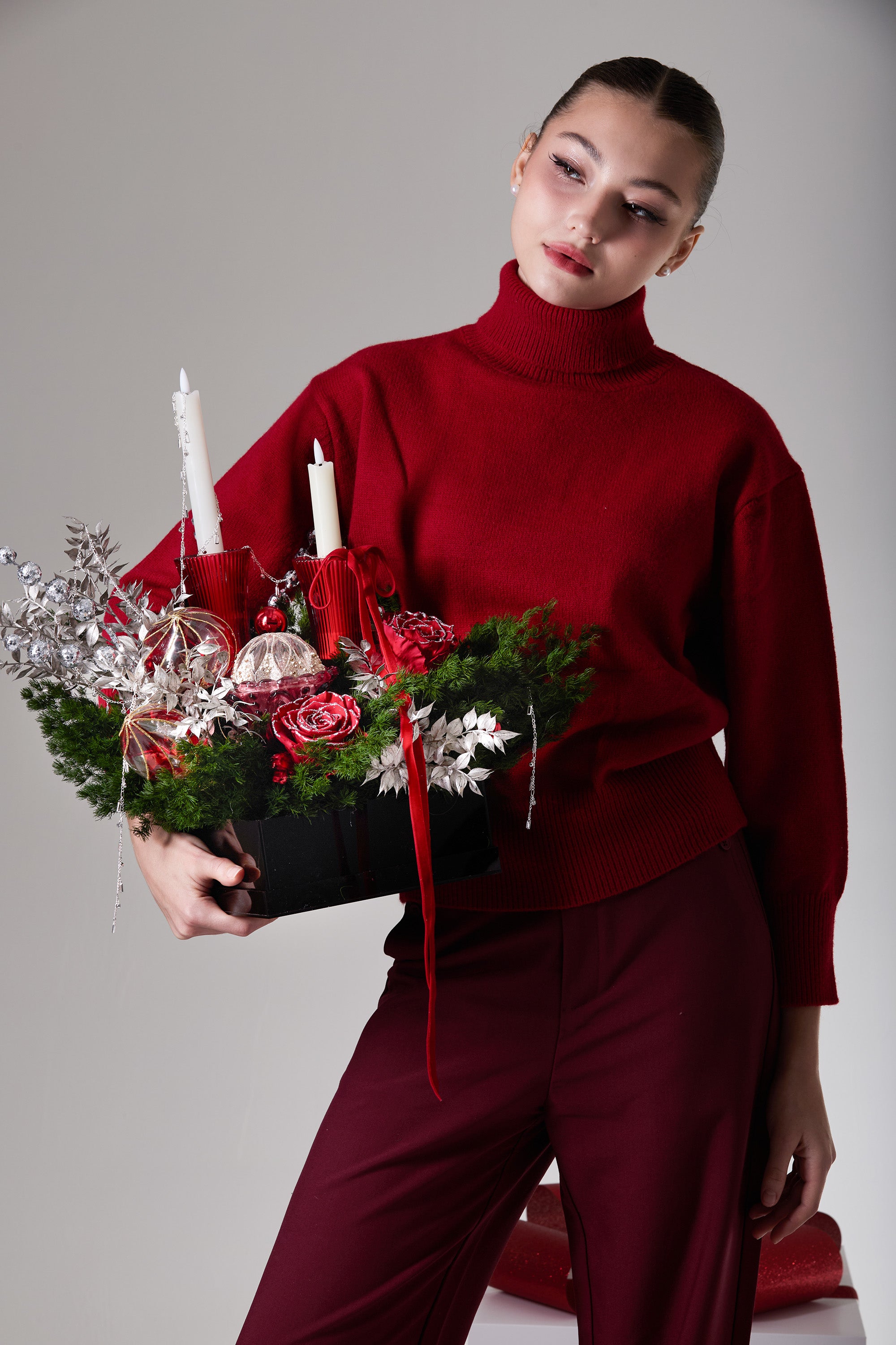 Red Solstice preserved rose candle centerpiece held at an angle with red preserved roses, silver foliage and twin candles.