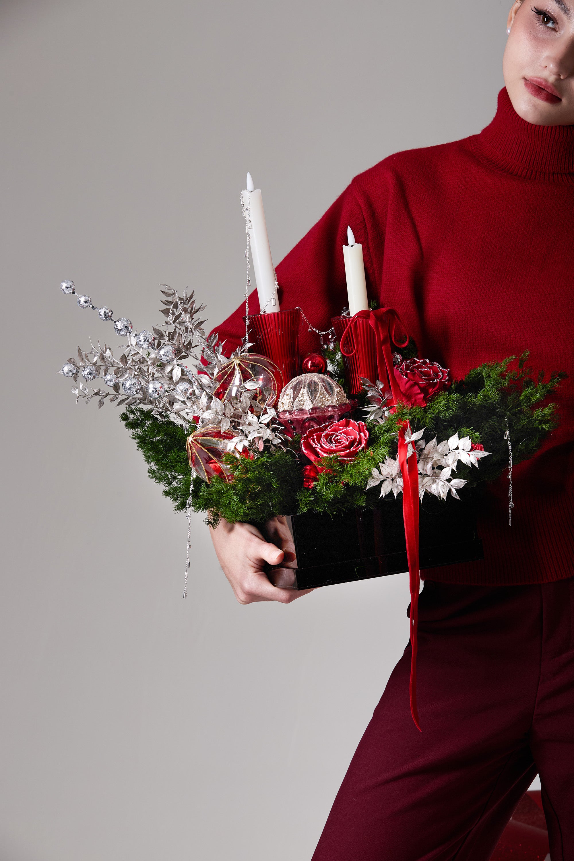 Red Solstice preserved rose arrangement close-up showing silver foliage, red ornament details and candle structure.