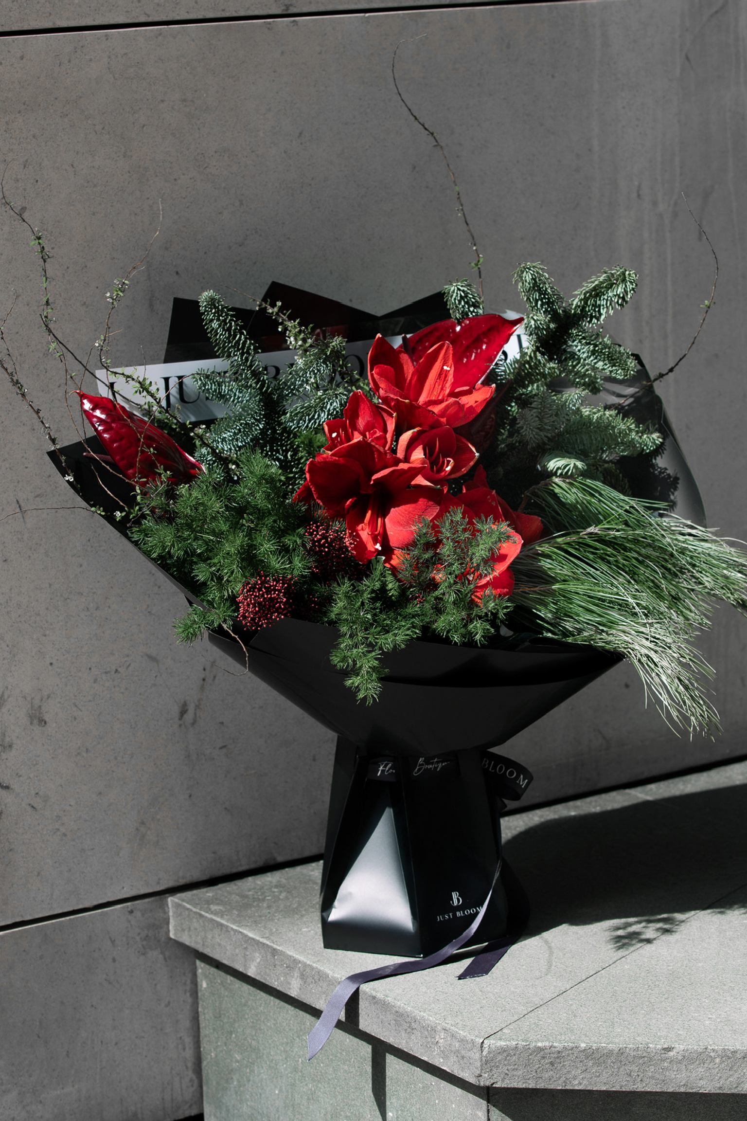 Red Vale bouquet featuring rich red florals with pine and fir foliage