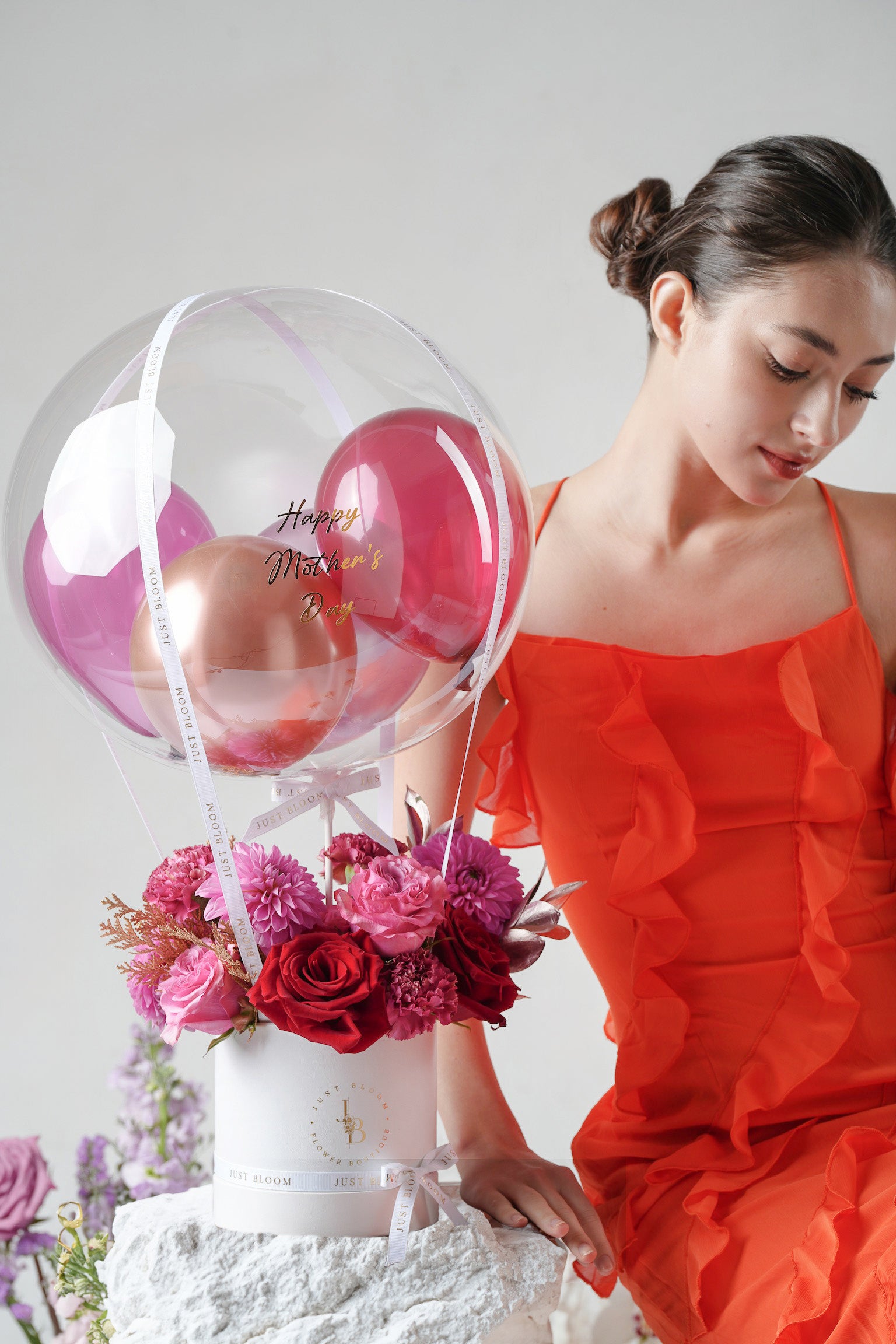 A bold and romantic floral hatbox with red roses, dahlias, and metallic foliage, topped with a crystal balloon.