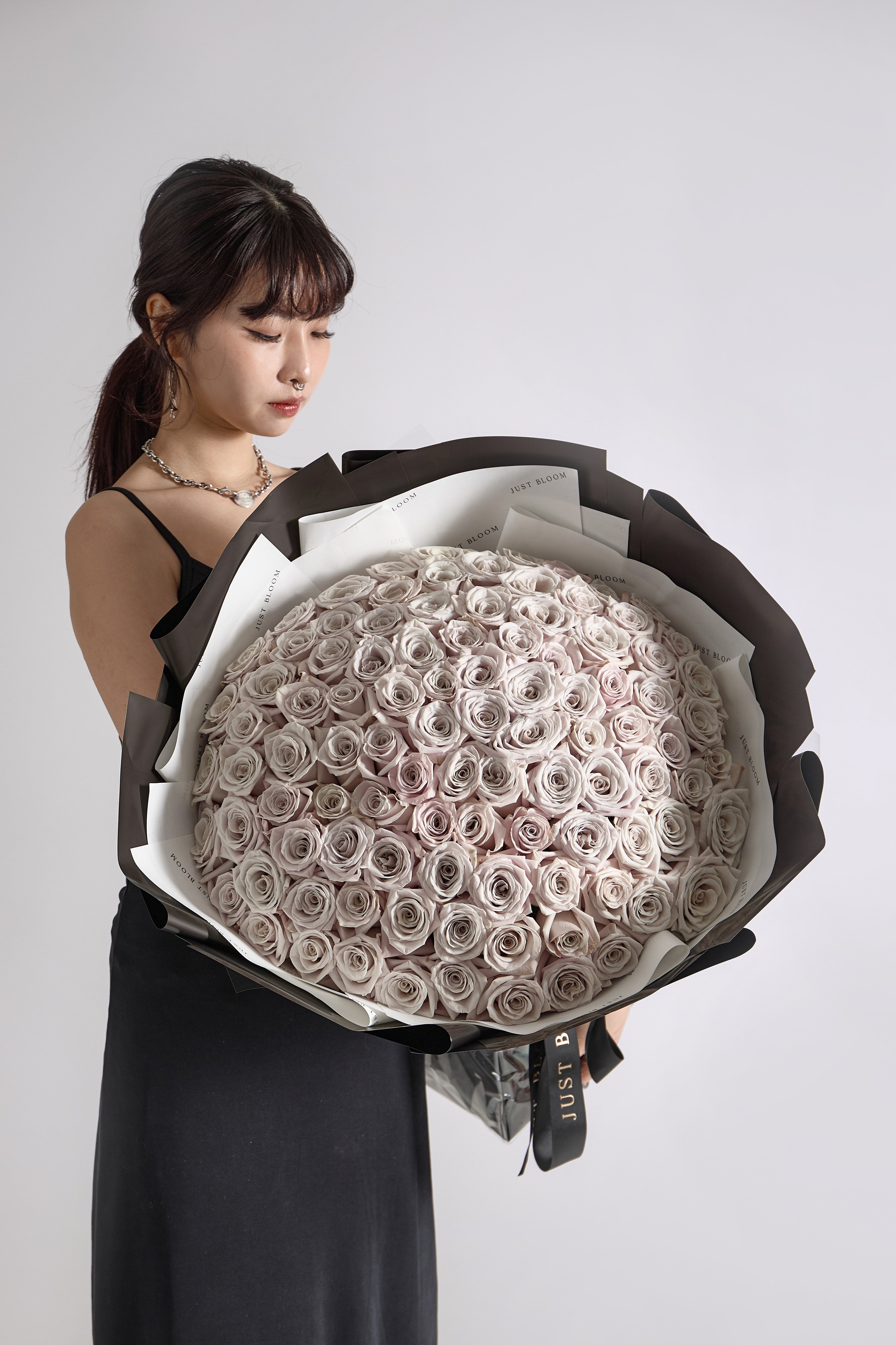 Large luxury bouquet of over 100 dusty pink roses in black and white wrapping arranged in dome shape