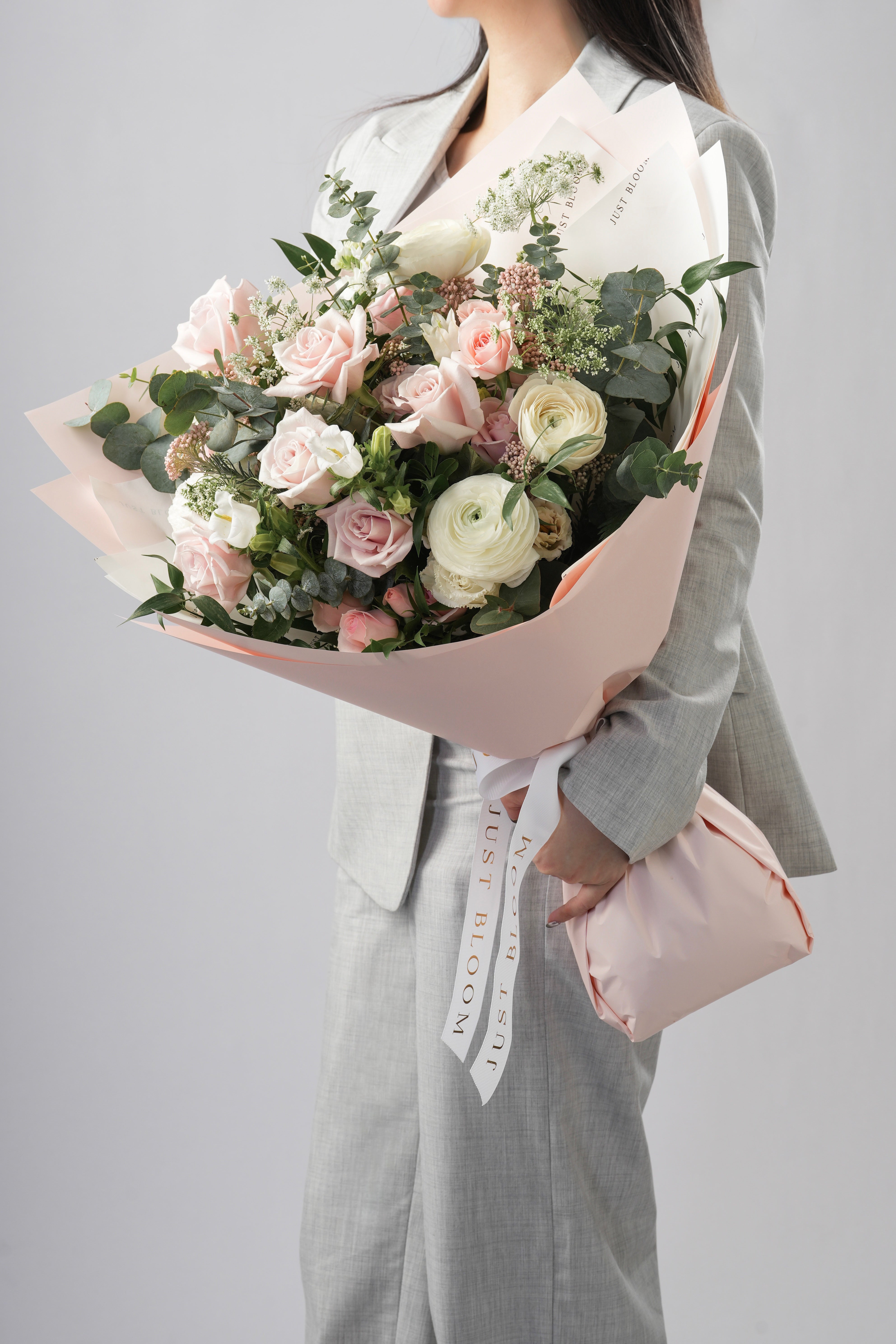 Serene bouquet with light pink roses, spray roses, ranunculus and greenery in soft pastel tones