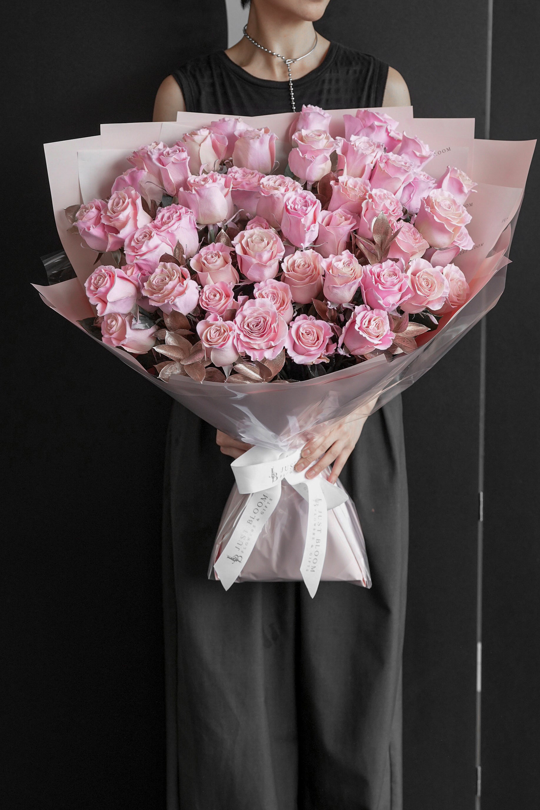 Model in a black dress holding the Soft Flush blush rose bouquet against a black backdrop — Just Bloom Hong Kong