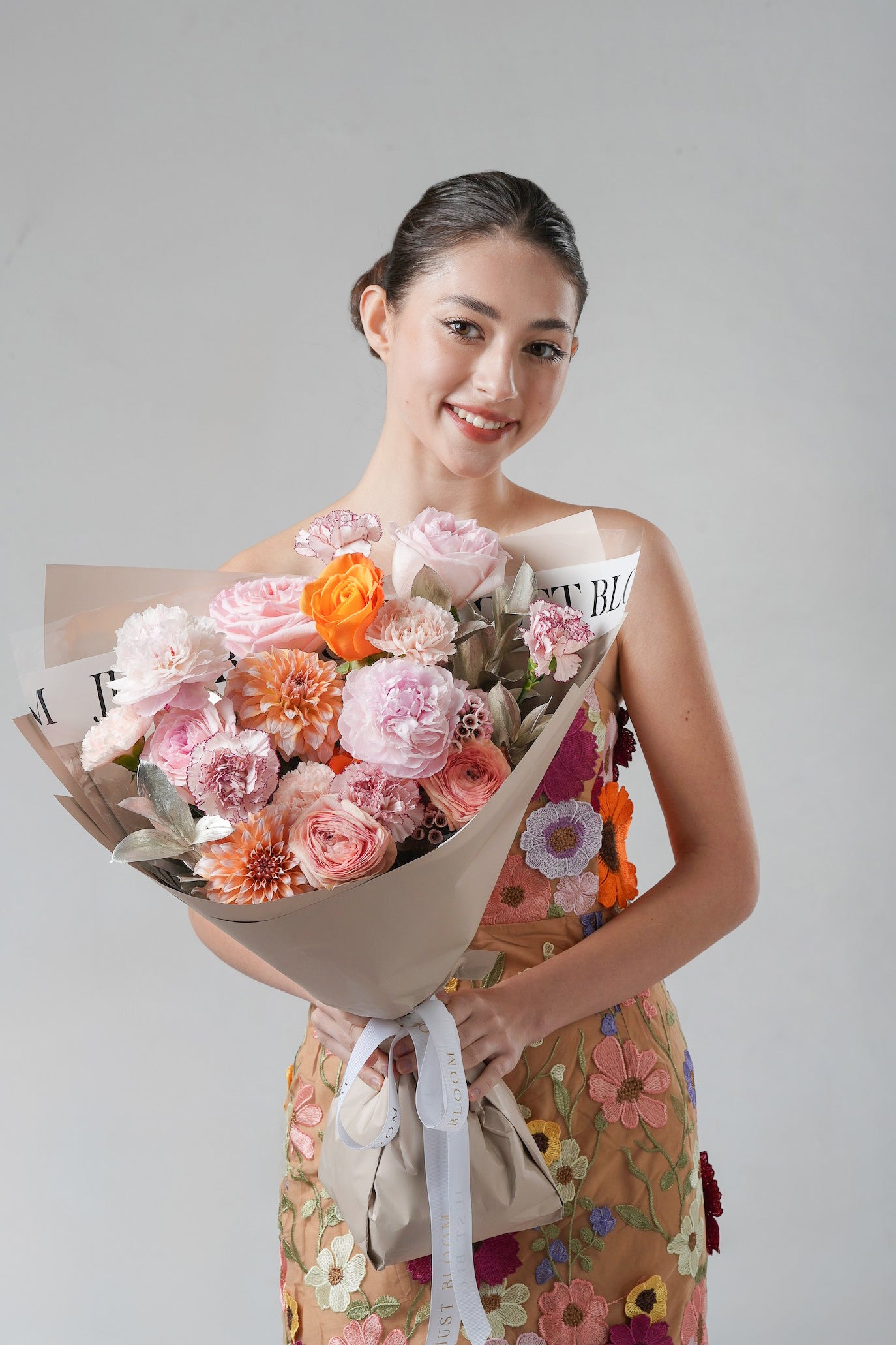 A warm-toned floral arrangement featuring dahlias, peonies, and garden roses in soft sunset hues.
