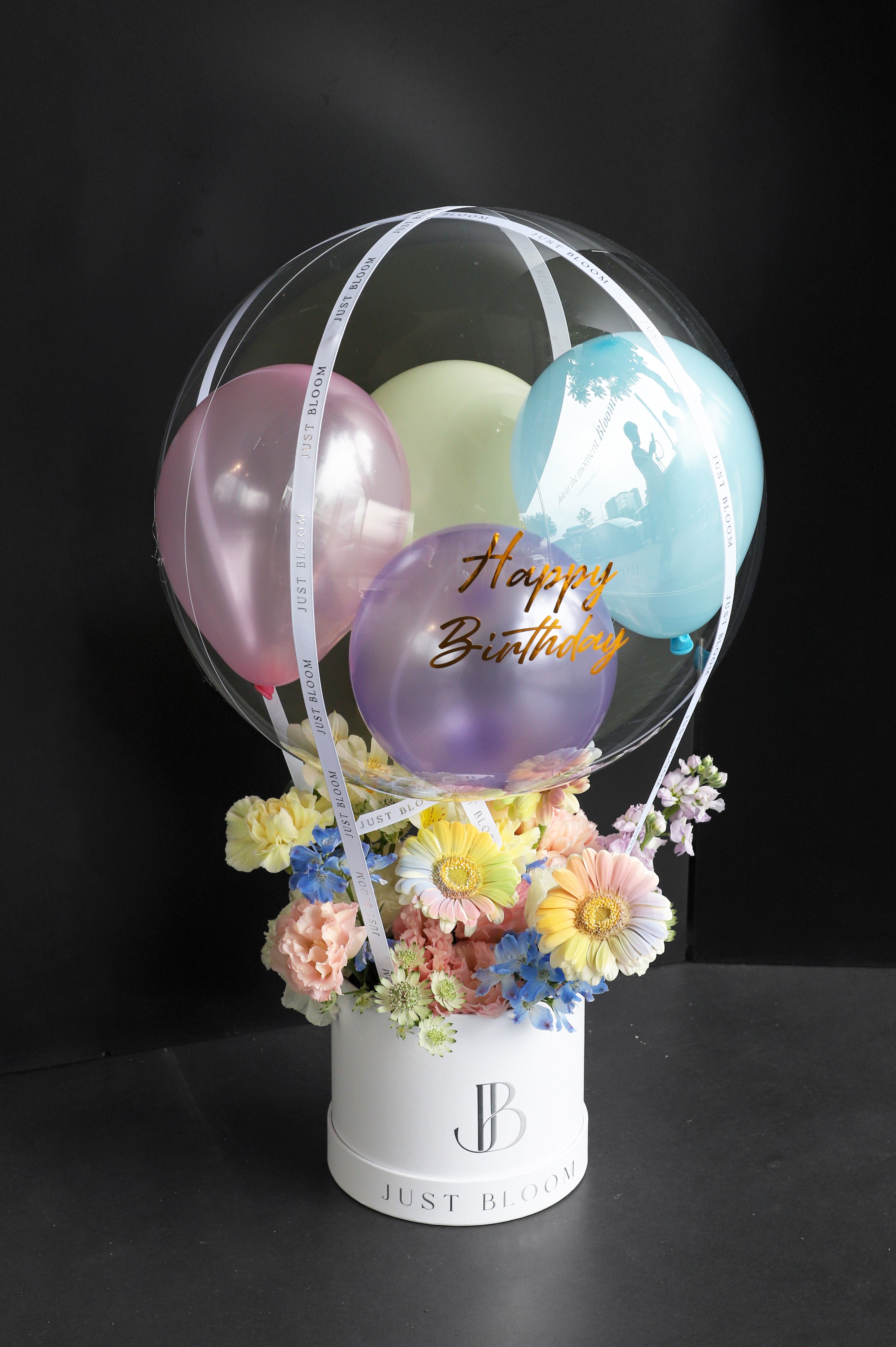 Playful pastel fresh flower box with Gerberas, Stocks, and blue seasonal blooms in a white Just Bloom round box against a dark background — Just Bloom Hong Kong