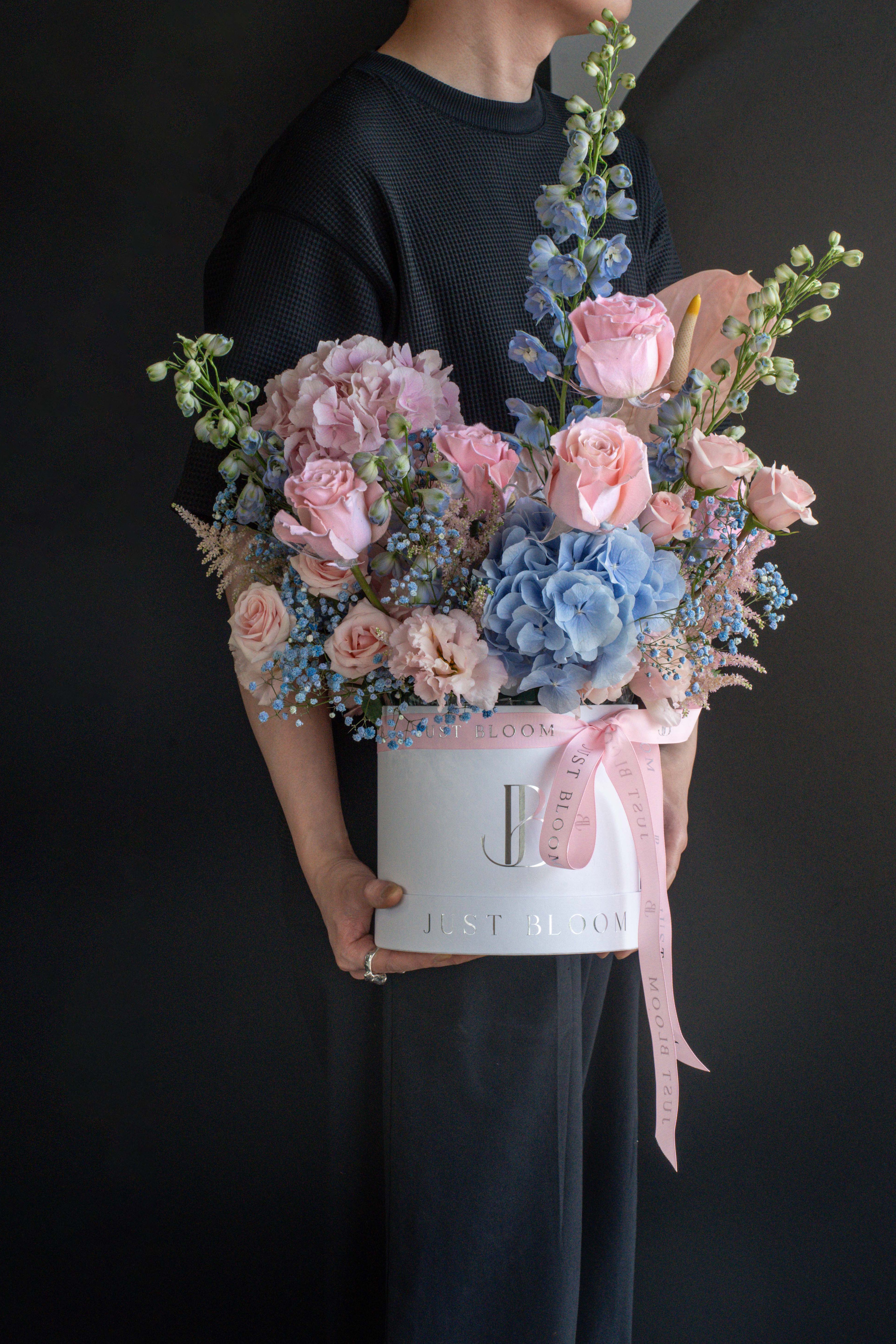 Person in black holding the Sweet Rhapsody pink and blue flower box against a black backdrop — Just Bloom Hong Kong