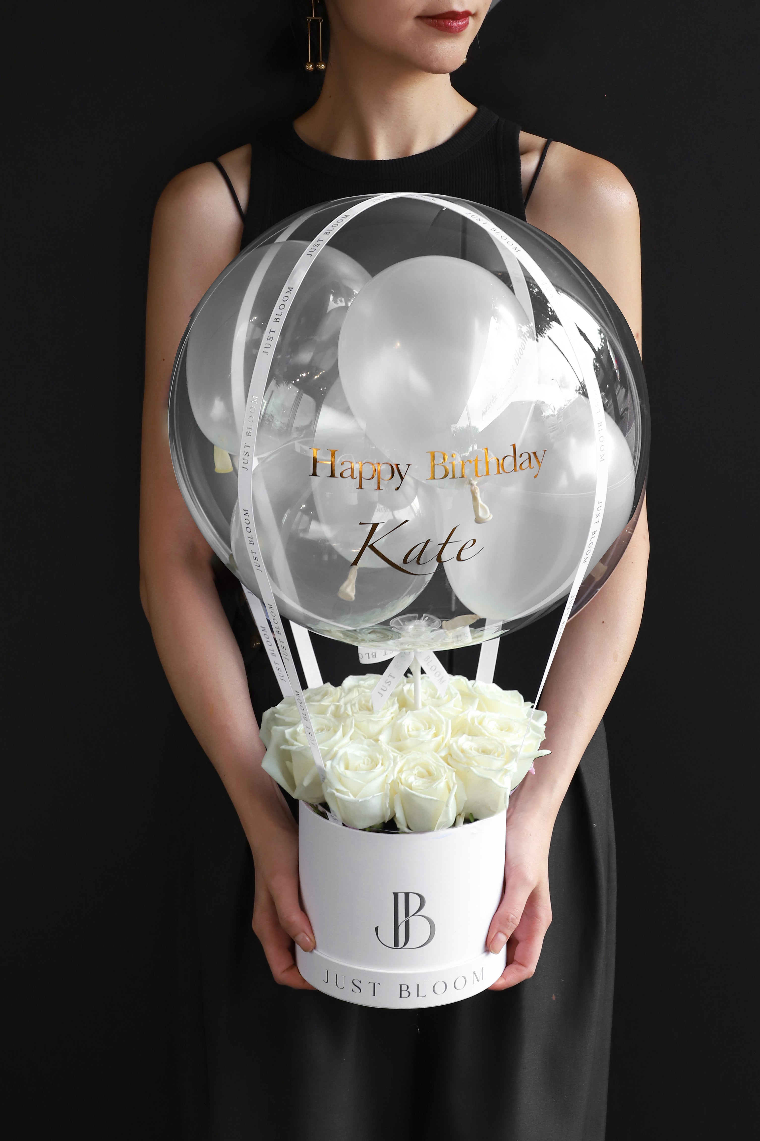 Model holding an all-white rose balloon flower box with a large crystal balloon containing white and clear balloons in a white Just Bloom round box against a dark background — Just Bloom Hong Kong