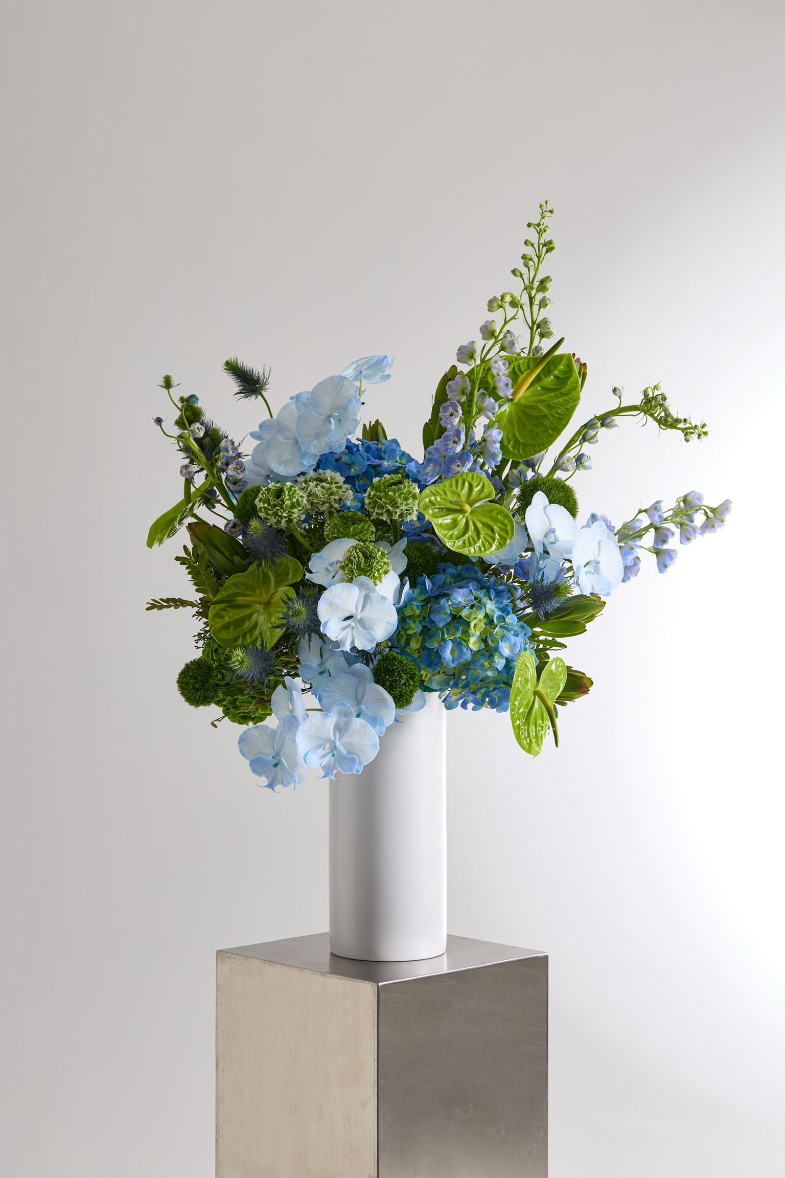 Verdant Blue Vase with Hydrangeas, Anthuriums, Delphiniums, Ranunculuses, Phalaenopsis Orchids, Eryngiums, and Green Trick Dianthuses by Just Bloom Hong Kong